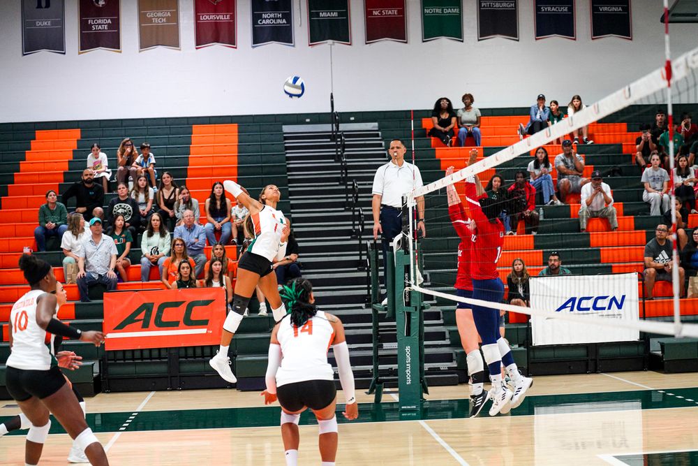 Volleyball player preparing to serve with knee pads and Miami uniform.