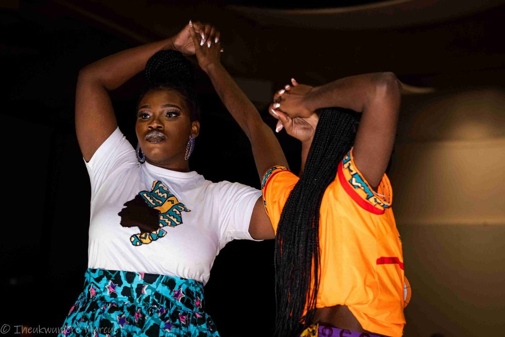 Two performers dancing energetically on stage in colorful outfits during a show.