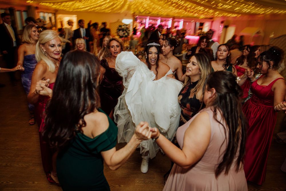 Wedding reception dance floor scene with guests lifting and celebrating in a festive tent. Quendon hall wedding, Irish fusion