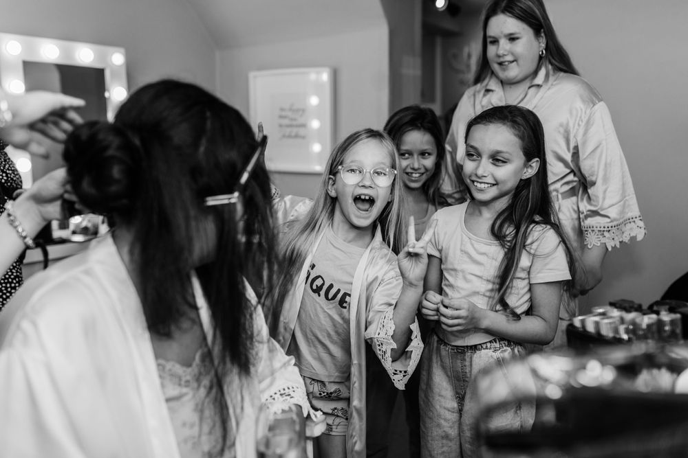Candid black and white photo of excited wedding party members reacting with joy. Bridal prep essex wedding photographer emotive