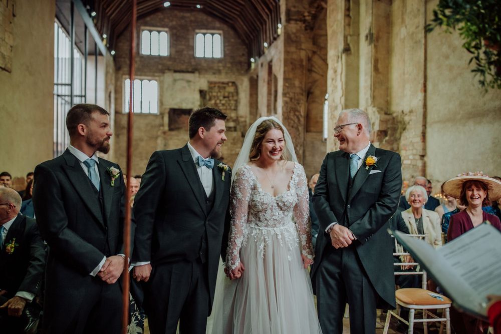 A wedding ceremony taking place in a rustic church interior with exposed brick walls and wooden beams.