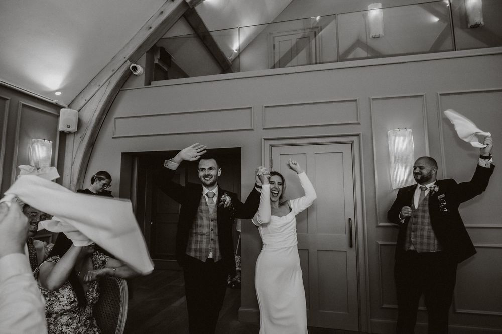 A series of black and white photos showing wedding guests joyfully dancing and celebrating during a reception party.