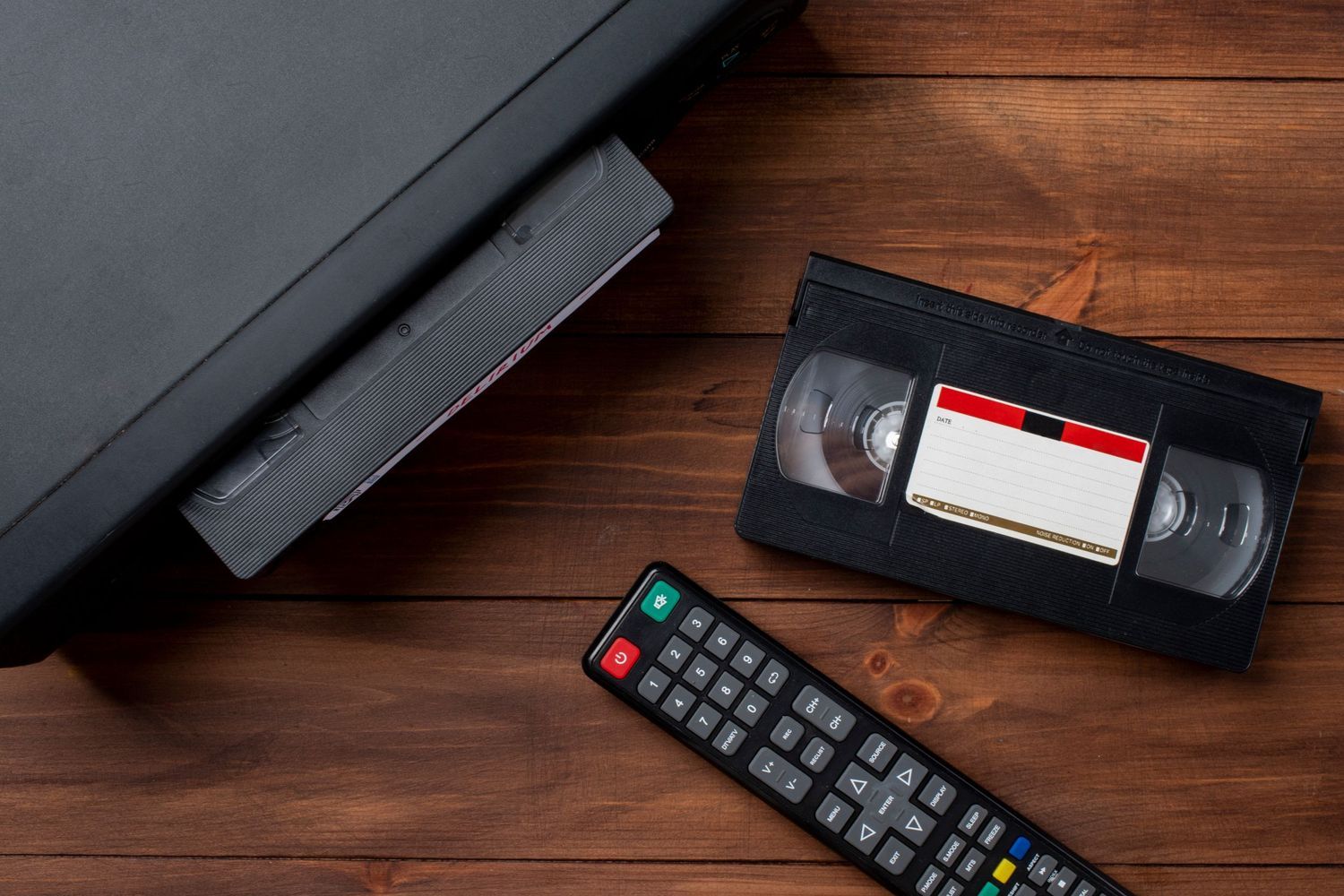 VHS predvajalnik s kaseto in daljincem na leseni podlagi kot prikaz stare video tehnologije Foto Colarič