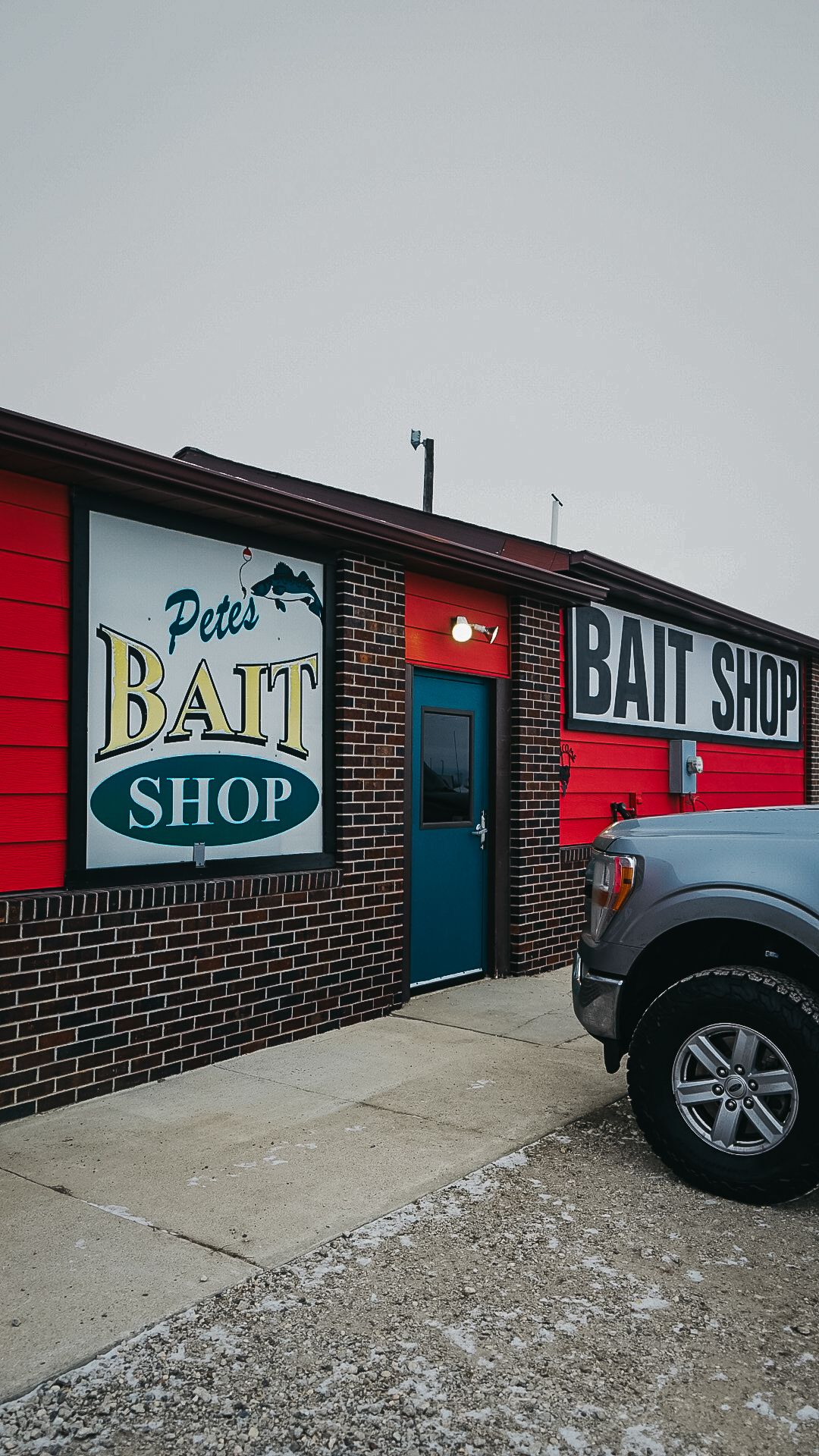 Exterior view of a bait shop with red and blue signage on brick building.