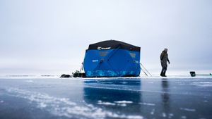 Ice fishing shelters and figures on a frozen lake against a misty winter horizon.