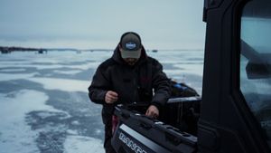 Ice fishing scene with equipment and shelters visible on frozen lake.
