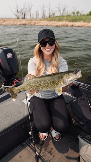 Angler displays a large northern pike caught while fishing from a boat.