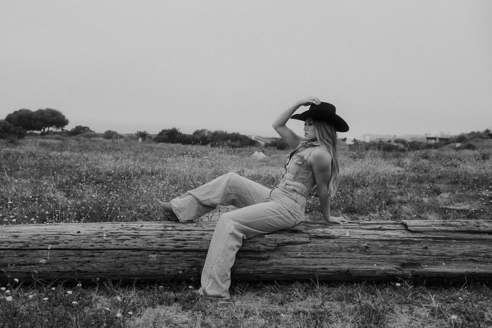 Black and white western style photo showing casual attire on a rustic log.