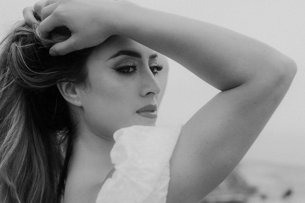Dramatic black and white portrait showing someone in a white top with windswept hair.