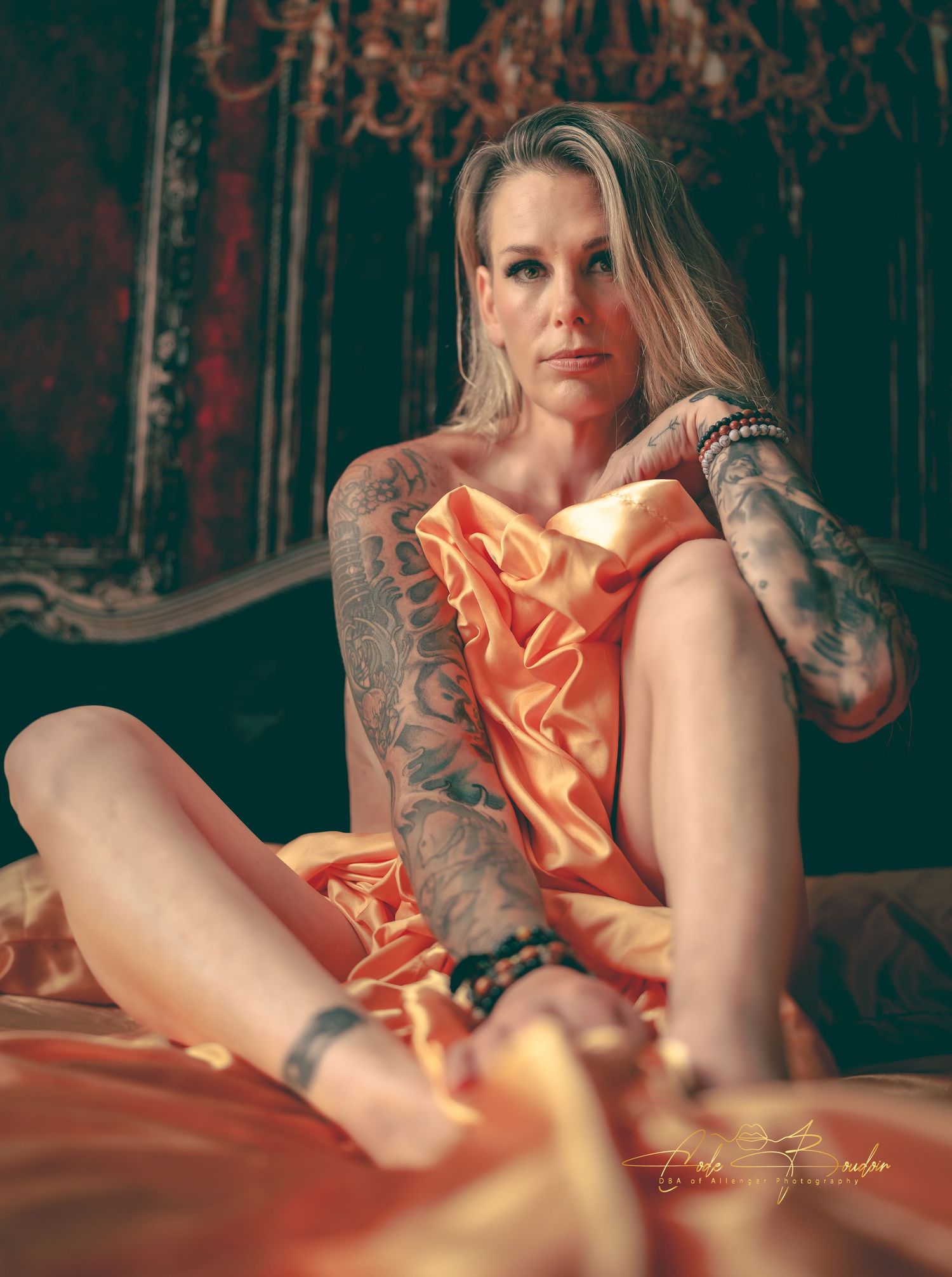 Photo of a lady during a boudoir shoot, covering her body with gold silky sheets in Rockport, Texas