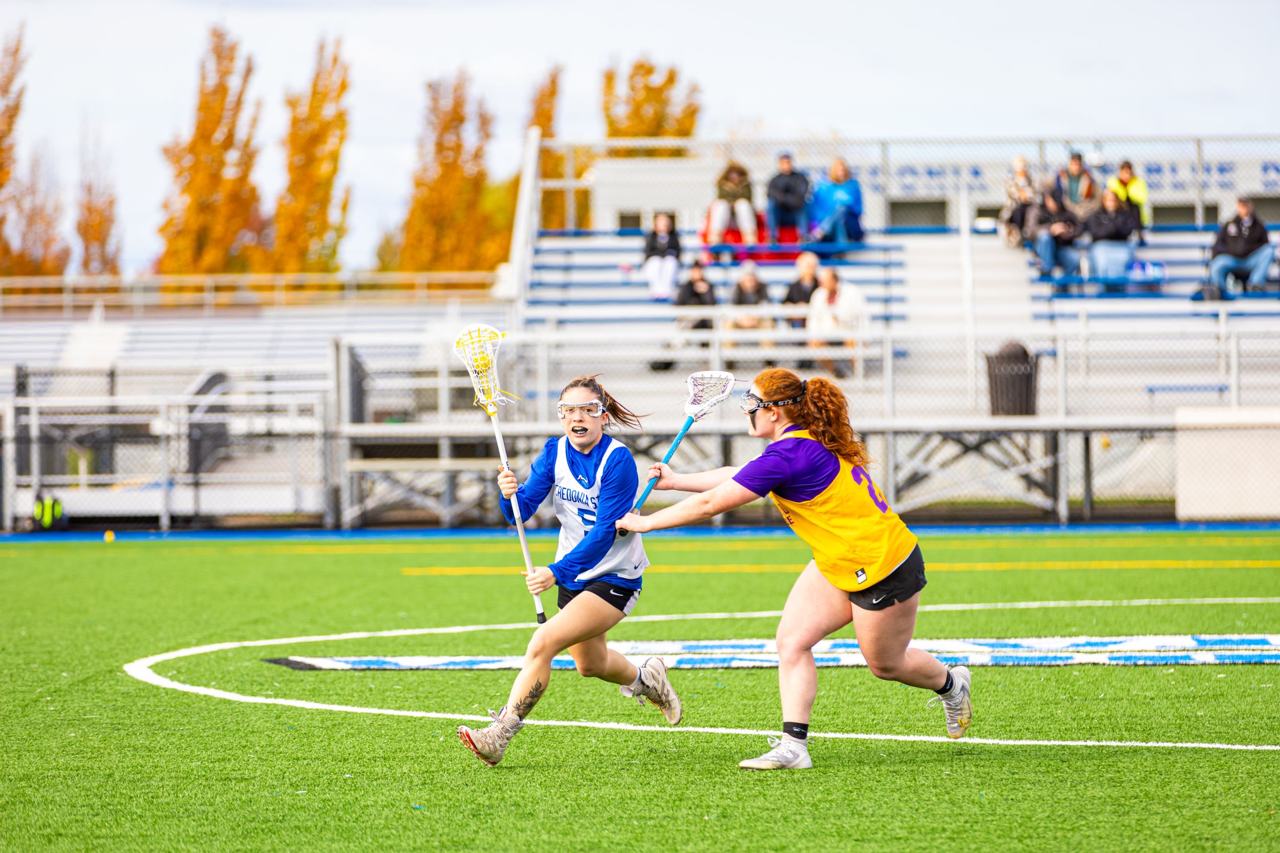 Soccer players diving for the ball on a green turf field during an intense match.