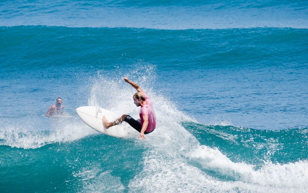 Dynamic surfing action shot showing aerial maneuver on a breaking turquoise wave.