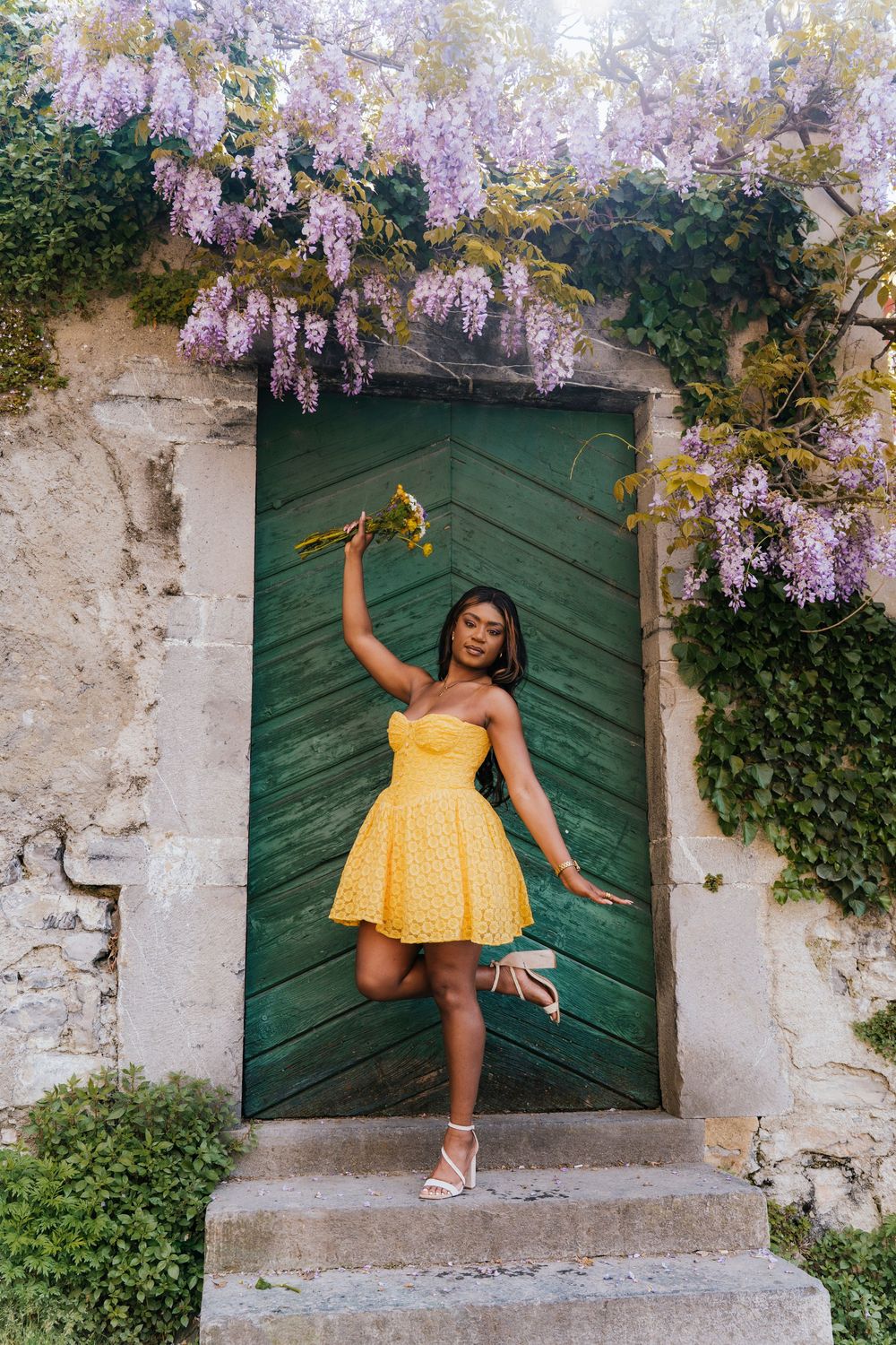 Fashion portrait series against rustic wall with wisteria flowers and green door.