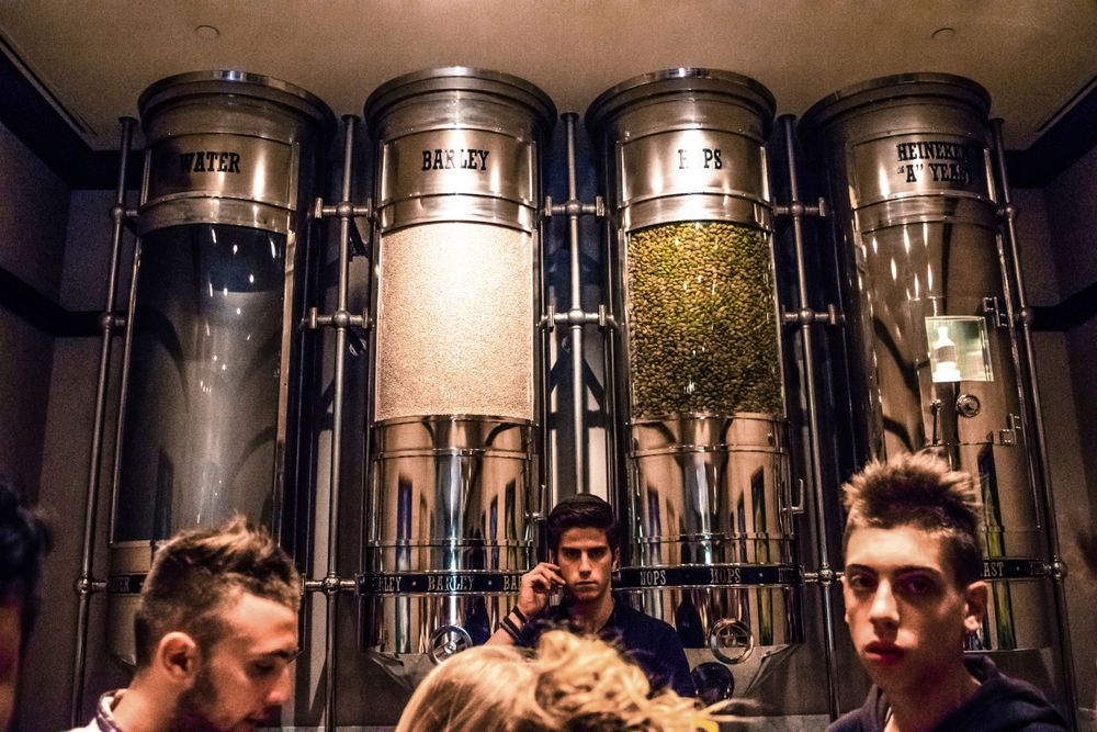 Metal dispensers containing different brewing ingredients in industrial setting.