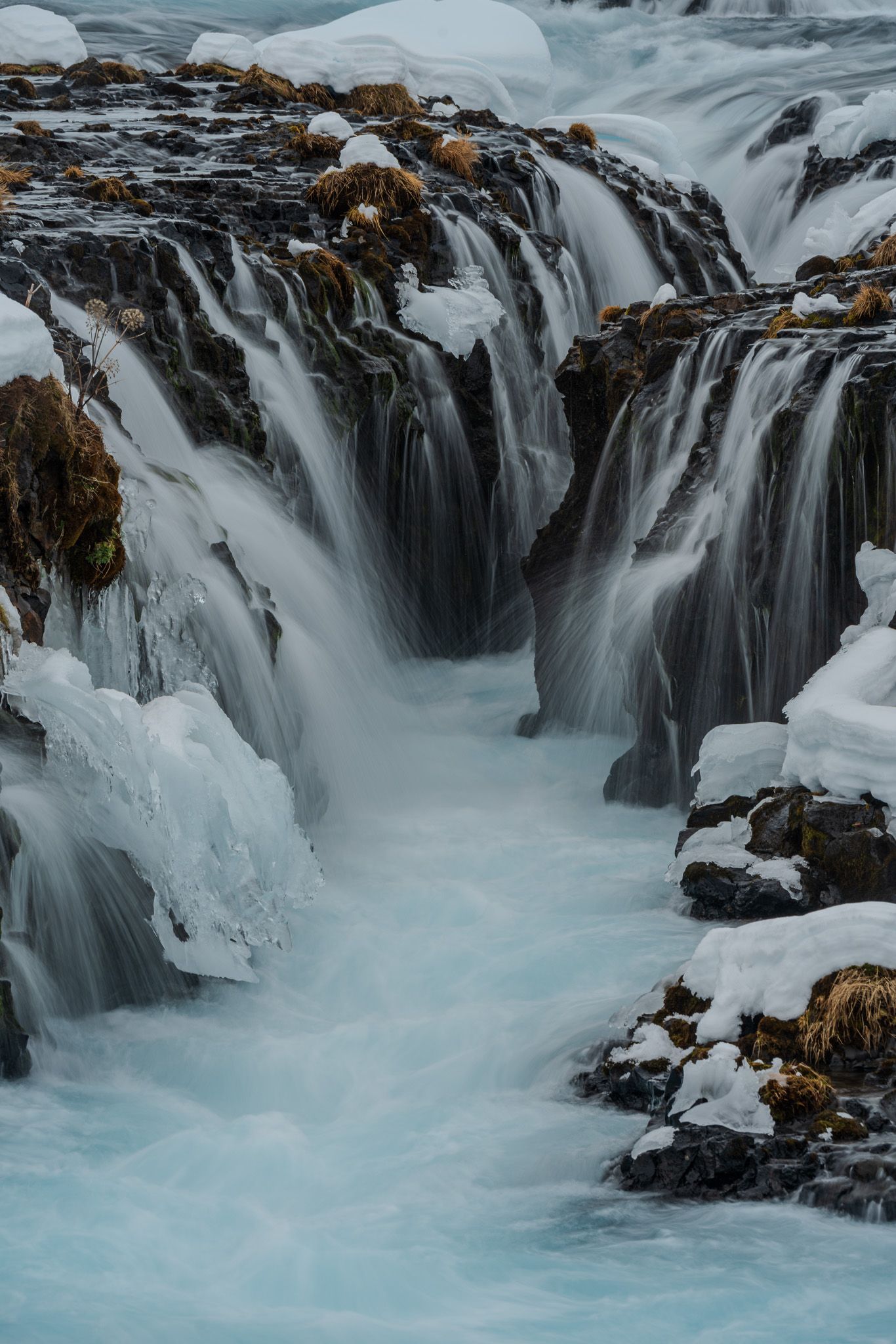 Bruarfoss, an unusual Icelandic waterfall with aqua blue glacial water cascades over a black basalt cavern.