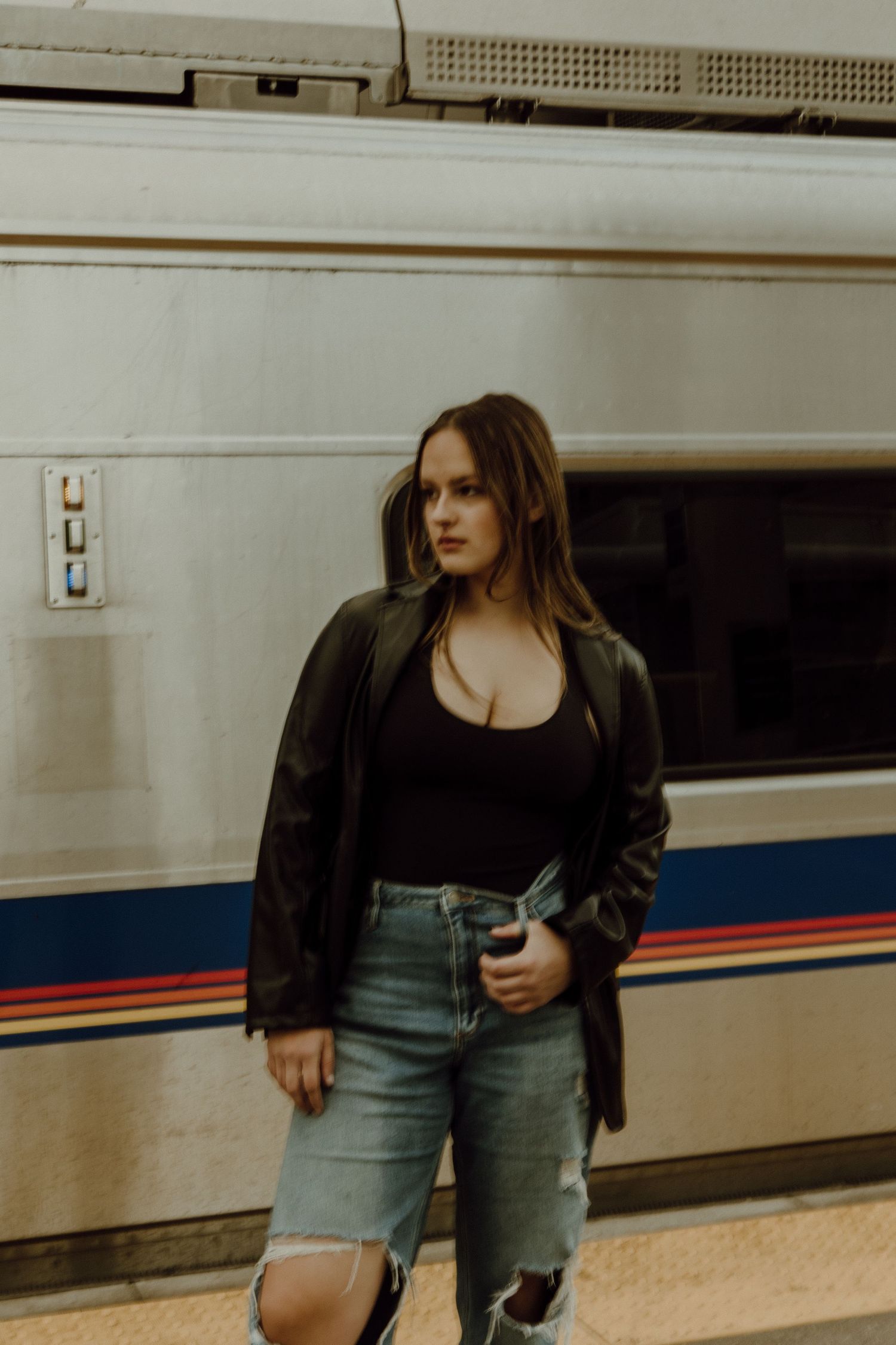 darker image of a woman looking to the left as a train moves behind her