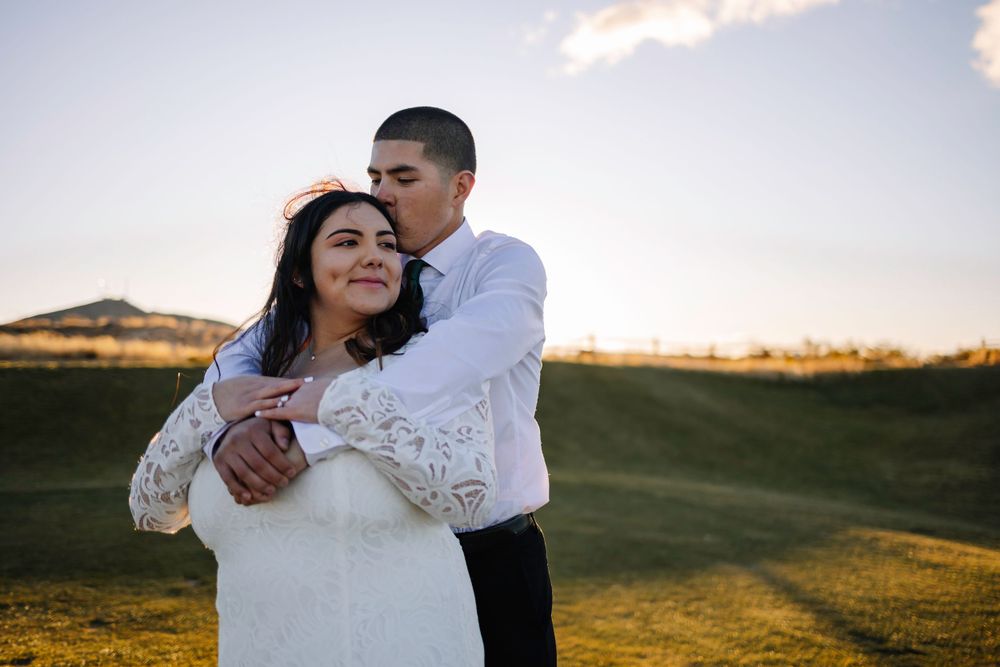 A tender embrace captured during sunset with mountains in the background.