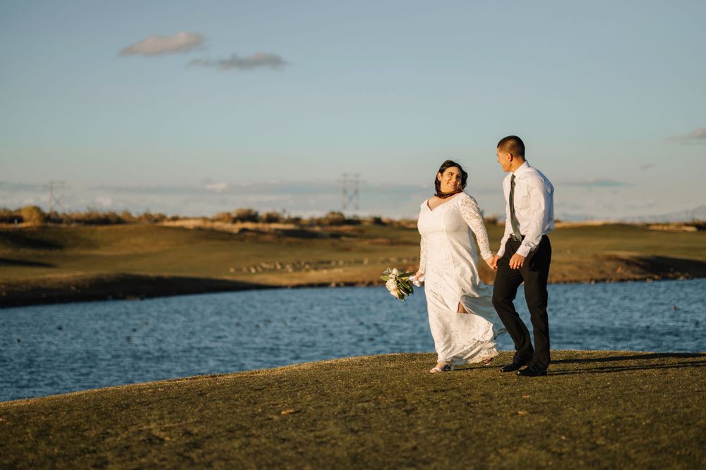 Wedding couple enjoying moment together by lake during sunset.