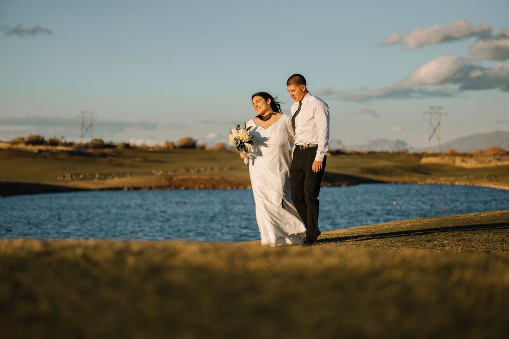 Couple walking along shoreline during sunset photoshoot.