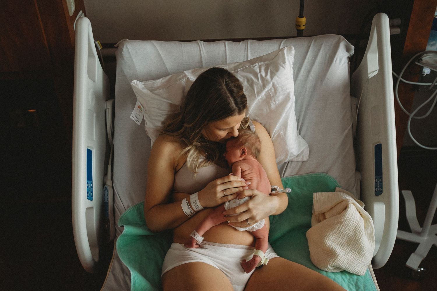 A gentle embrace between mother and newborn in a hospital bed.