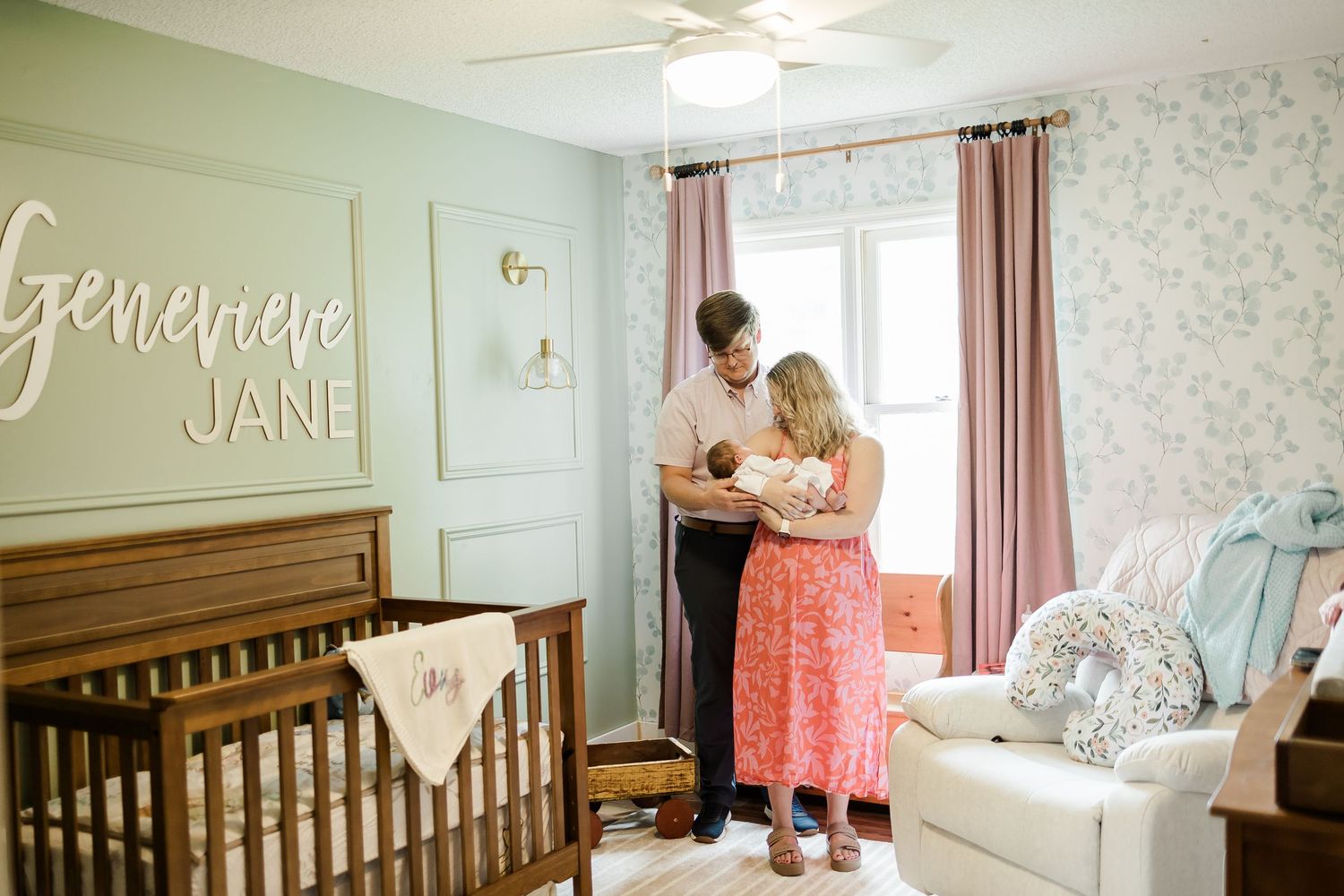 Soft mint green nursery with floral wallpaper and wooden crib.