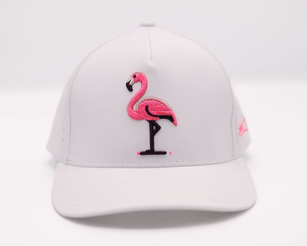 White baseball cap featuring a pink flamingo embroidered logo, structured fit with curved brim.