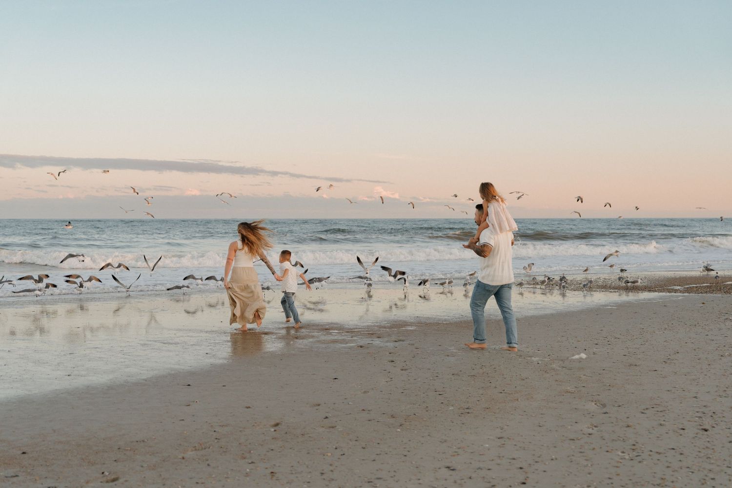 Romantic beach engagement photo during sunset with ocean waves in background.