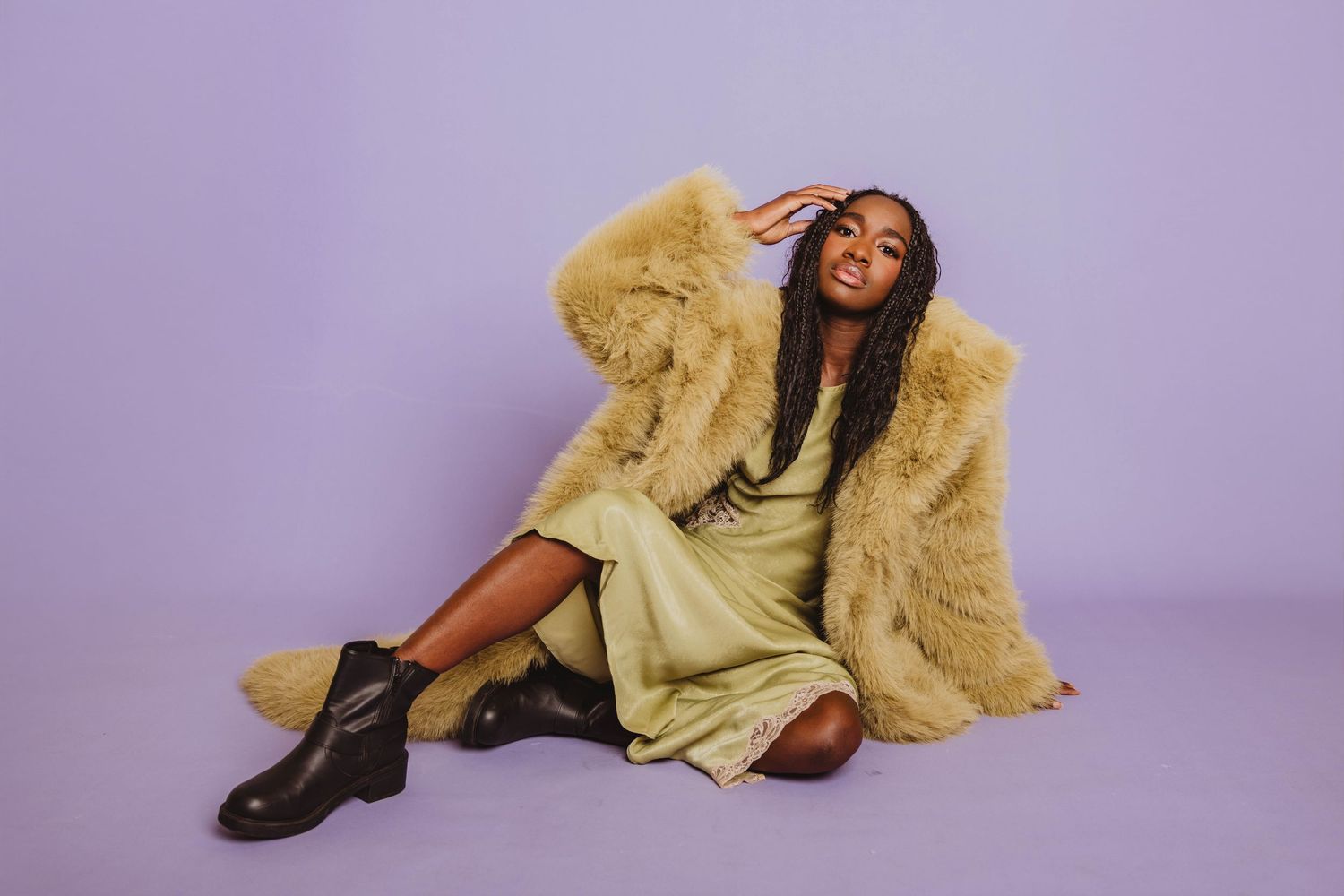 A person in a yellow dress and brown boots poses on a purple backdrop in a dynamic fashion photo series.