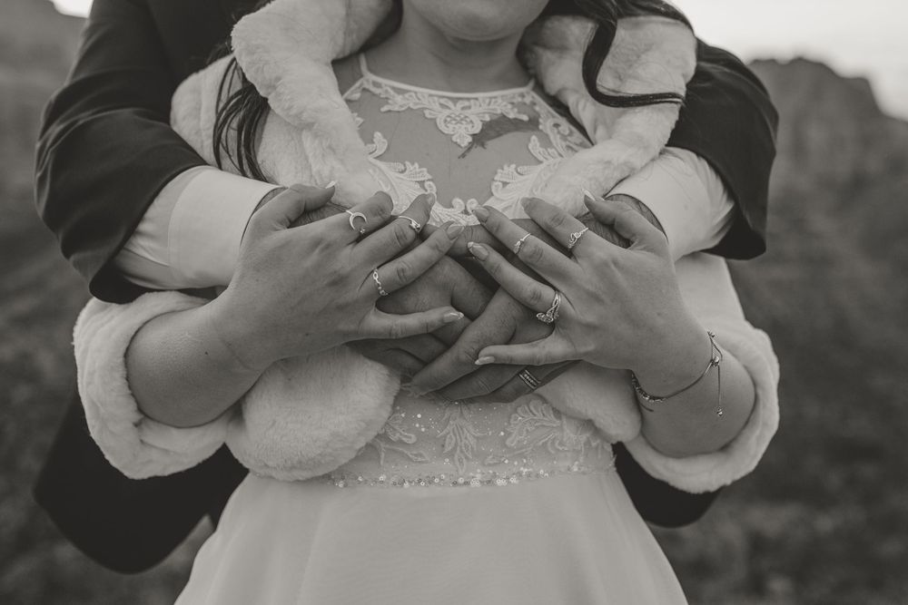Black and white photo showing hands cupping fine white powder in a delicate white dress detailed with lace.