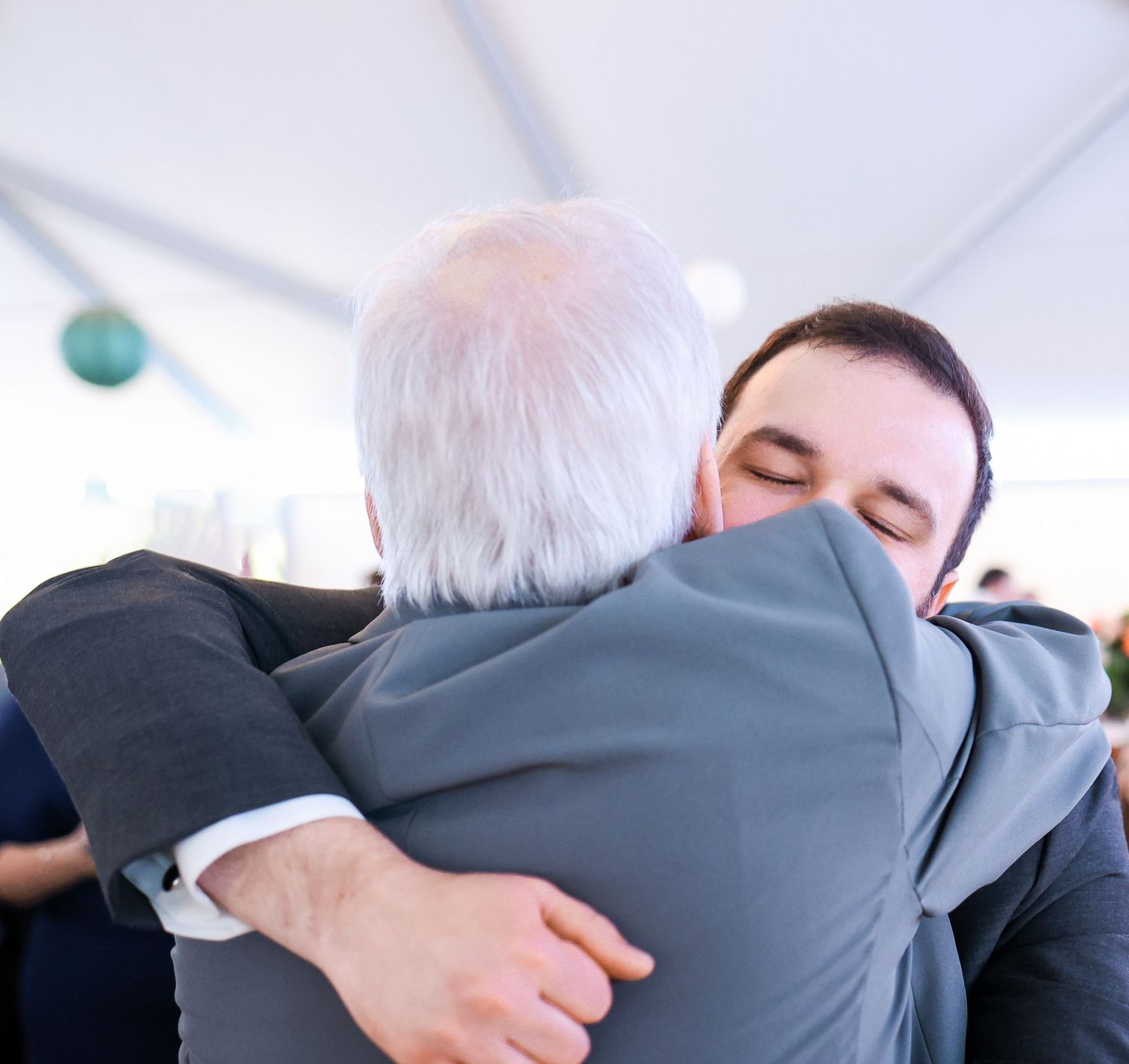 Emotional moment of a groom hugging a guest during wedding reception.