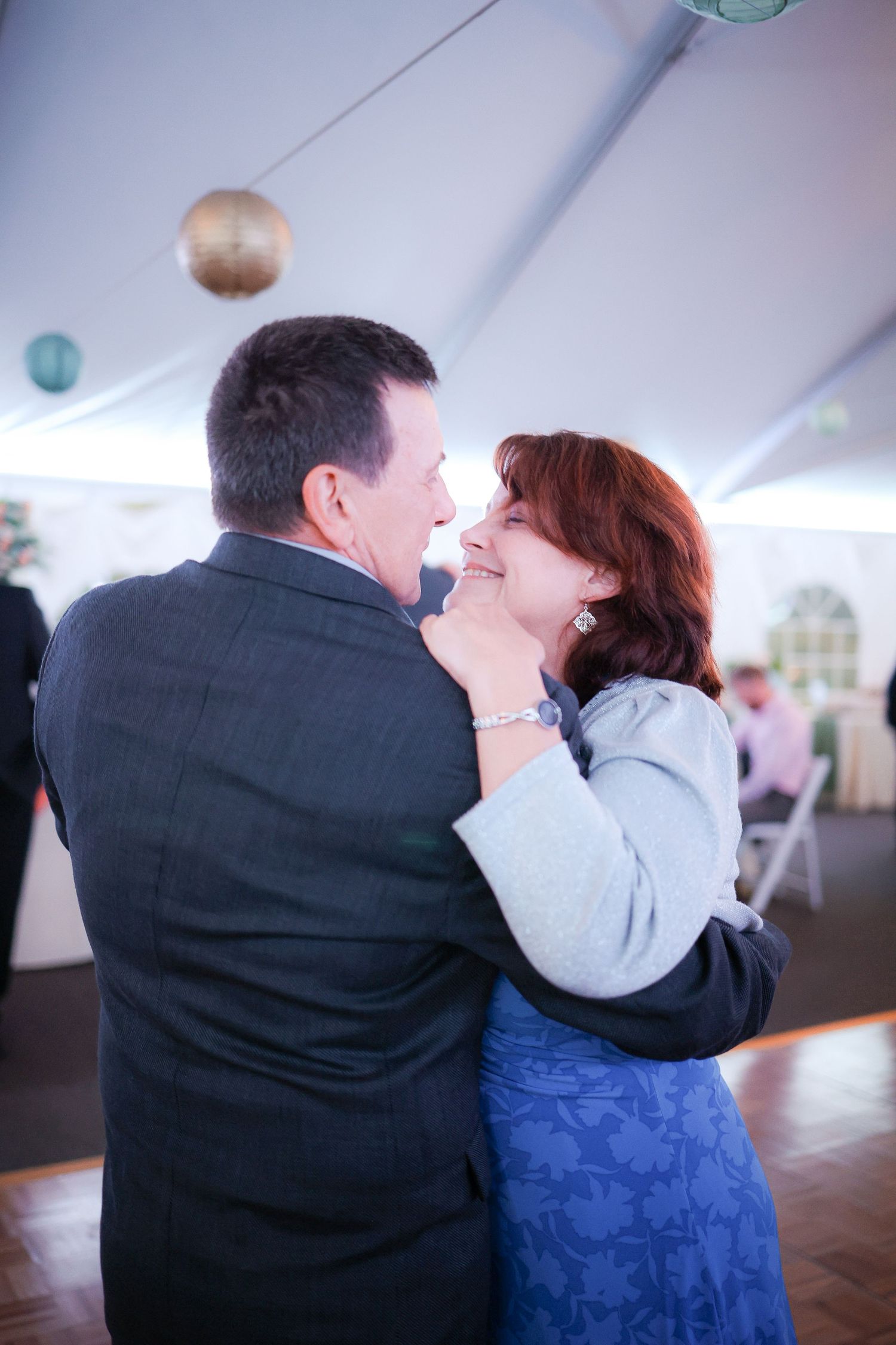 A couple sharing a romantic dance moment under a white tent at their wedding reception.