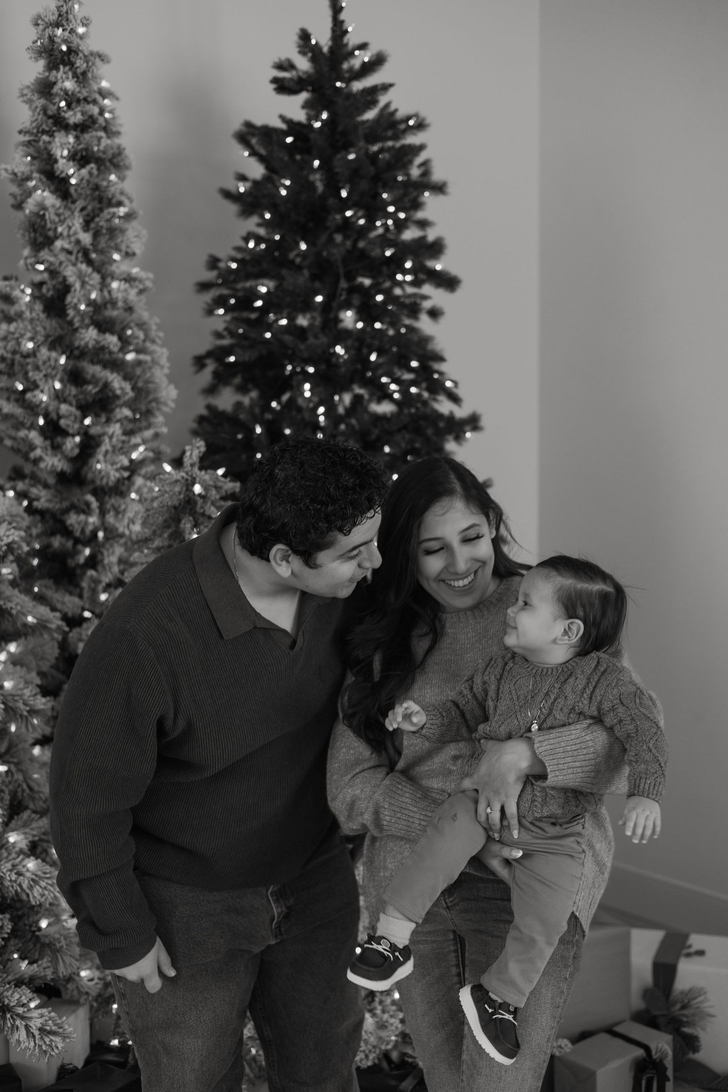 Heartwarming family moment by decorated Christmas trees with twinkling lights.