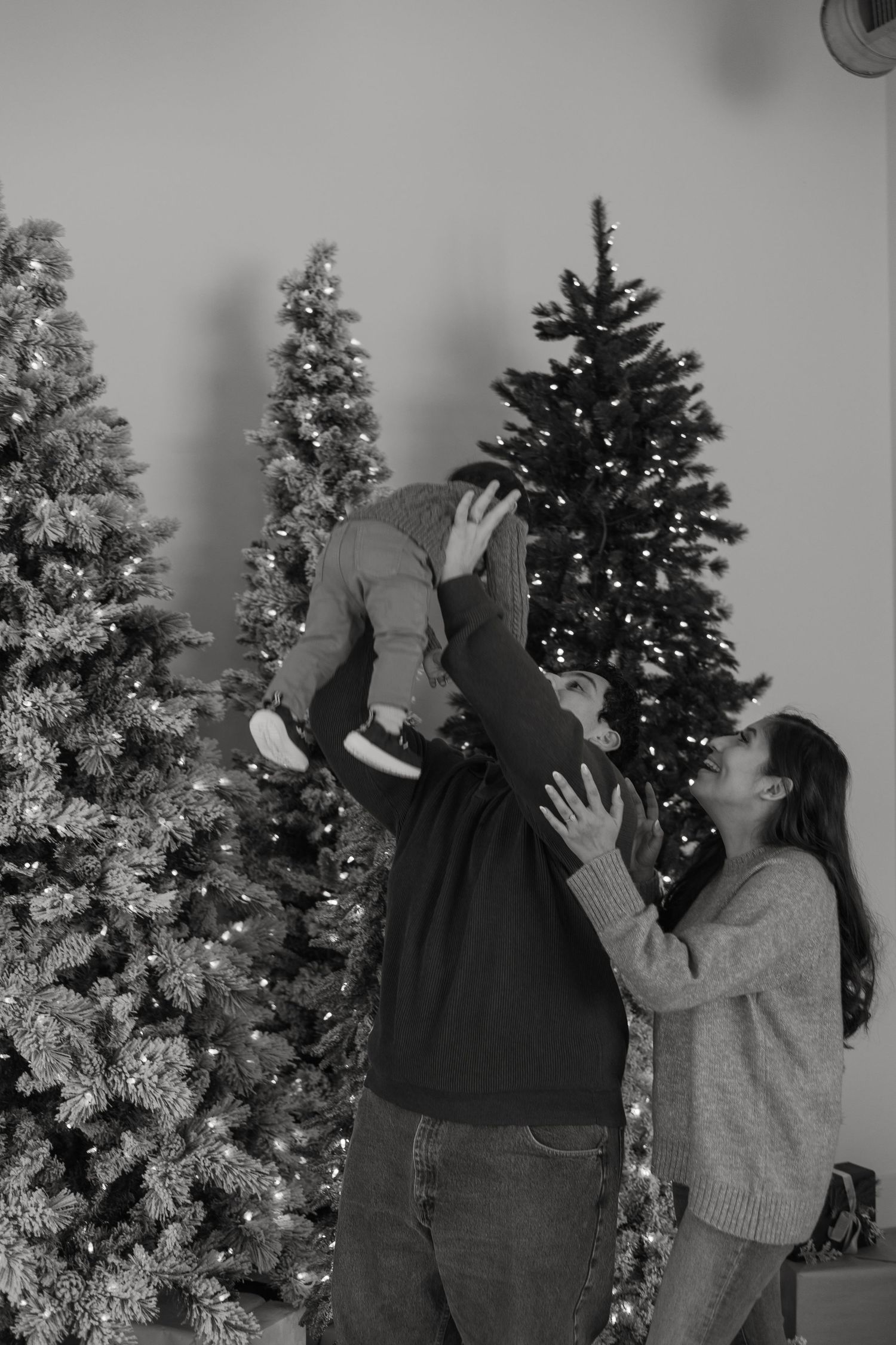Joyful family playtime captured in black and white with festive Christmas trees.