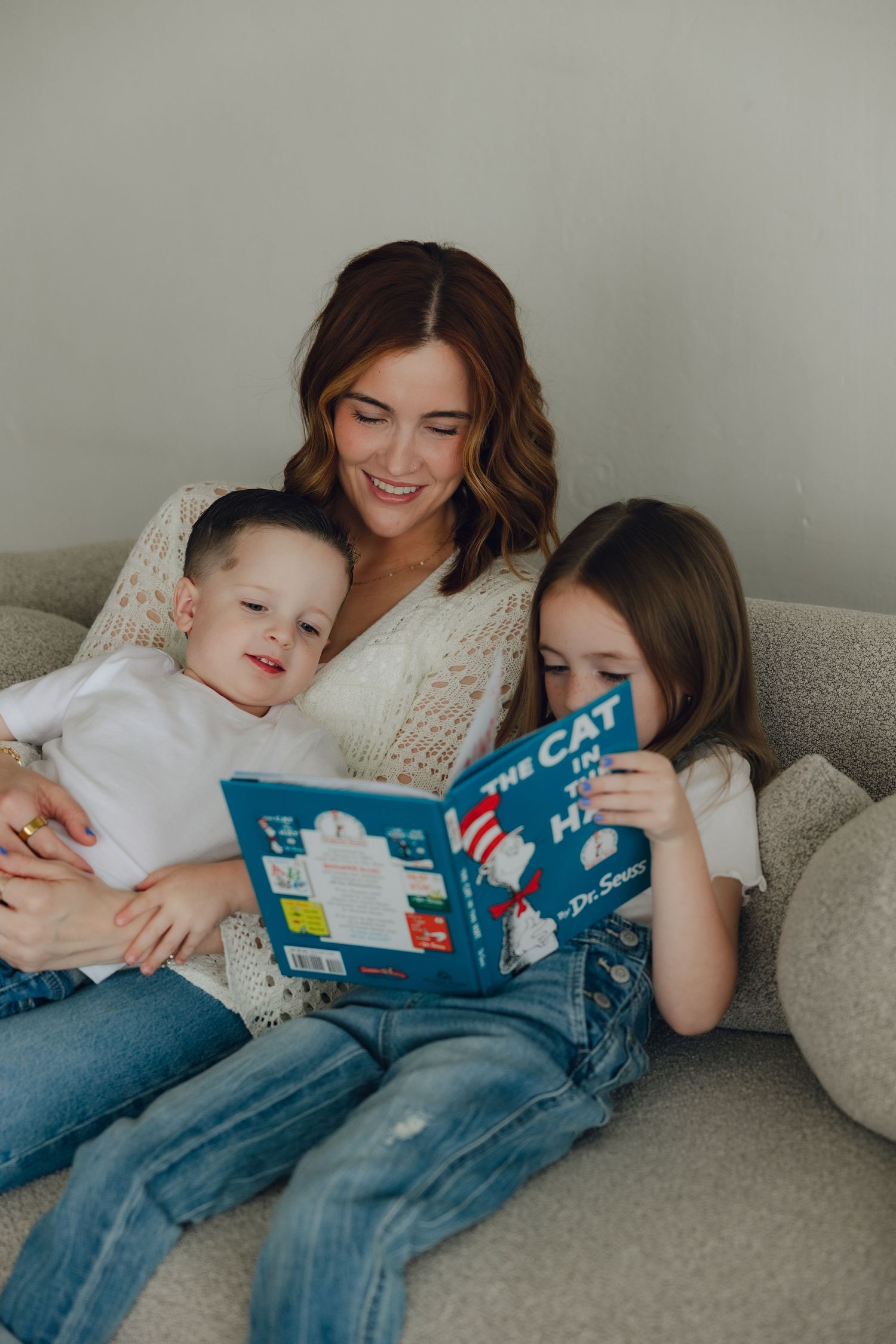 A cozy family moment on the sofa while reading a children's book together.