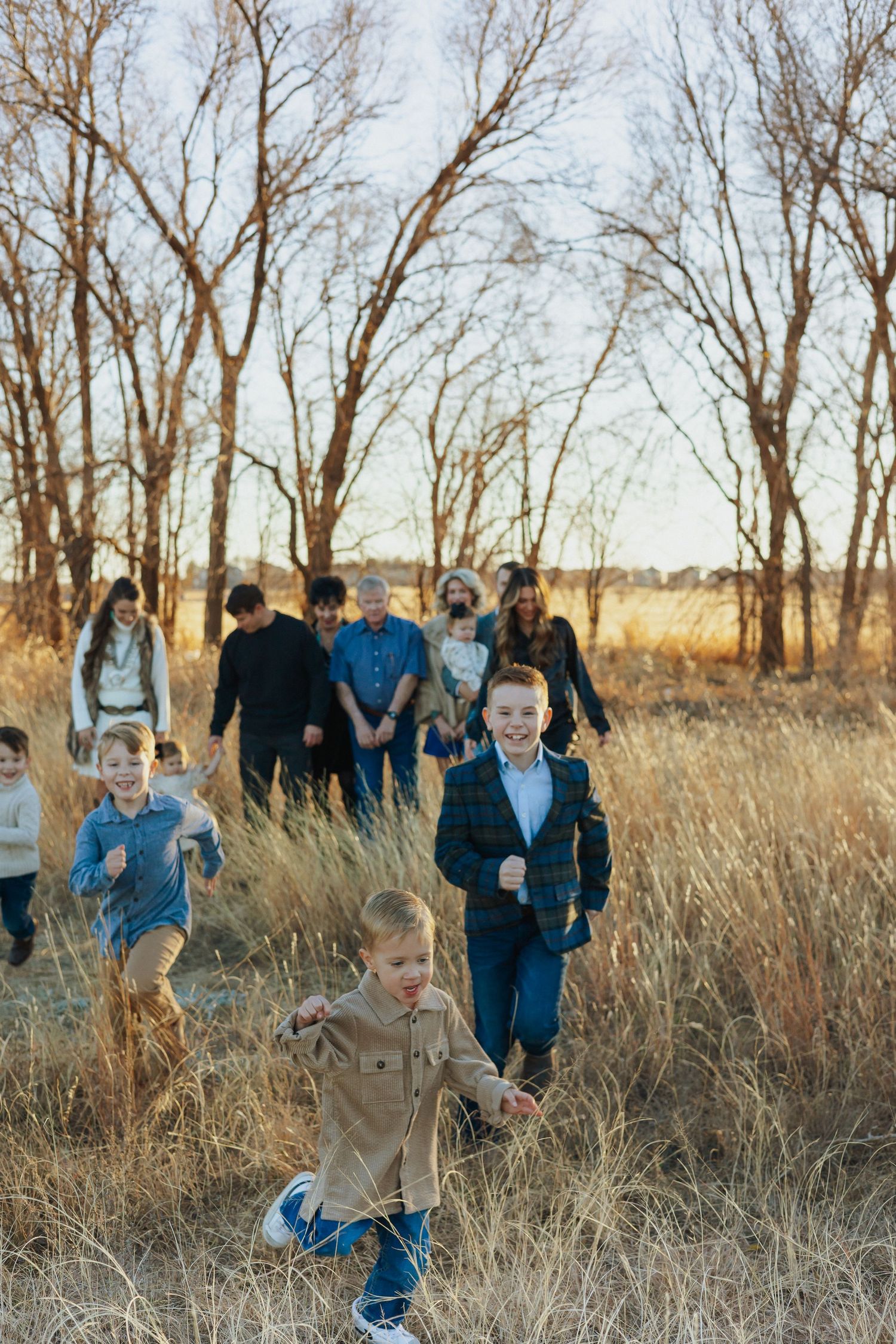 Children running through golden field with adults in background.