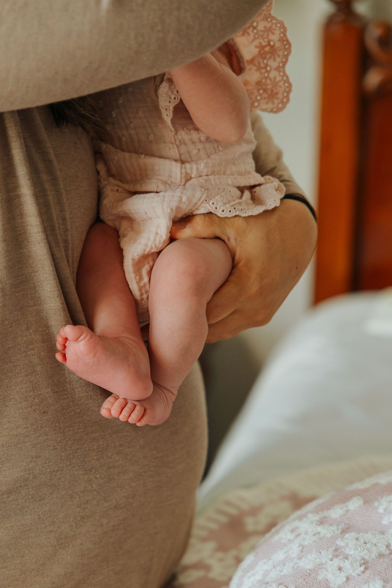 Close-up of tiny baby feet in delicate lace dress.