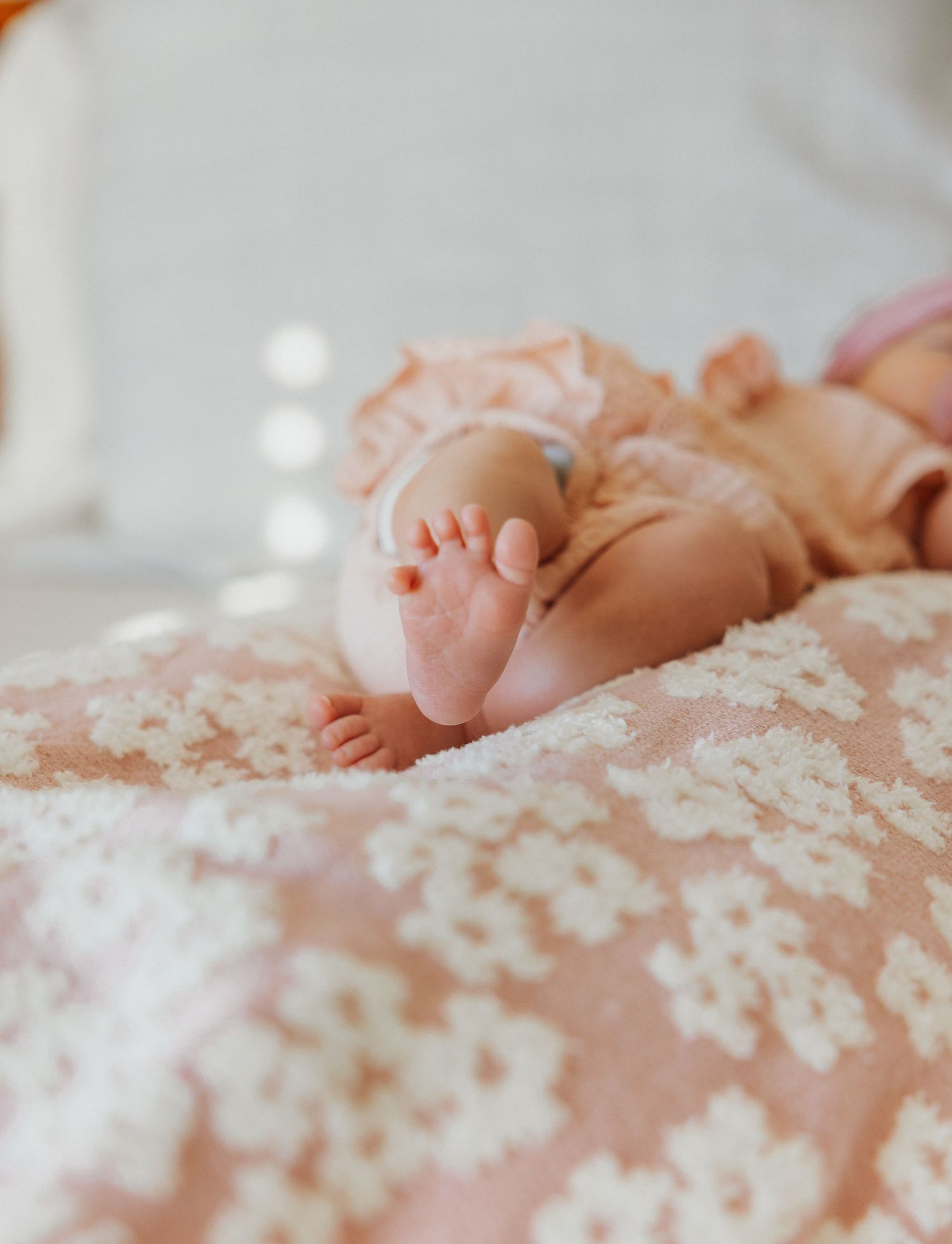 Close up of baby feet on floral patterned blanket.
