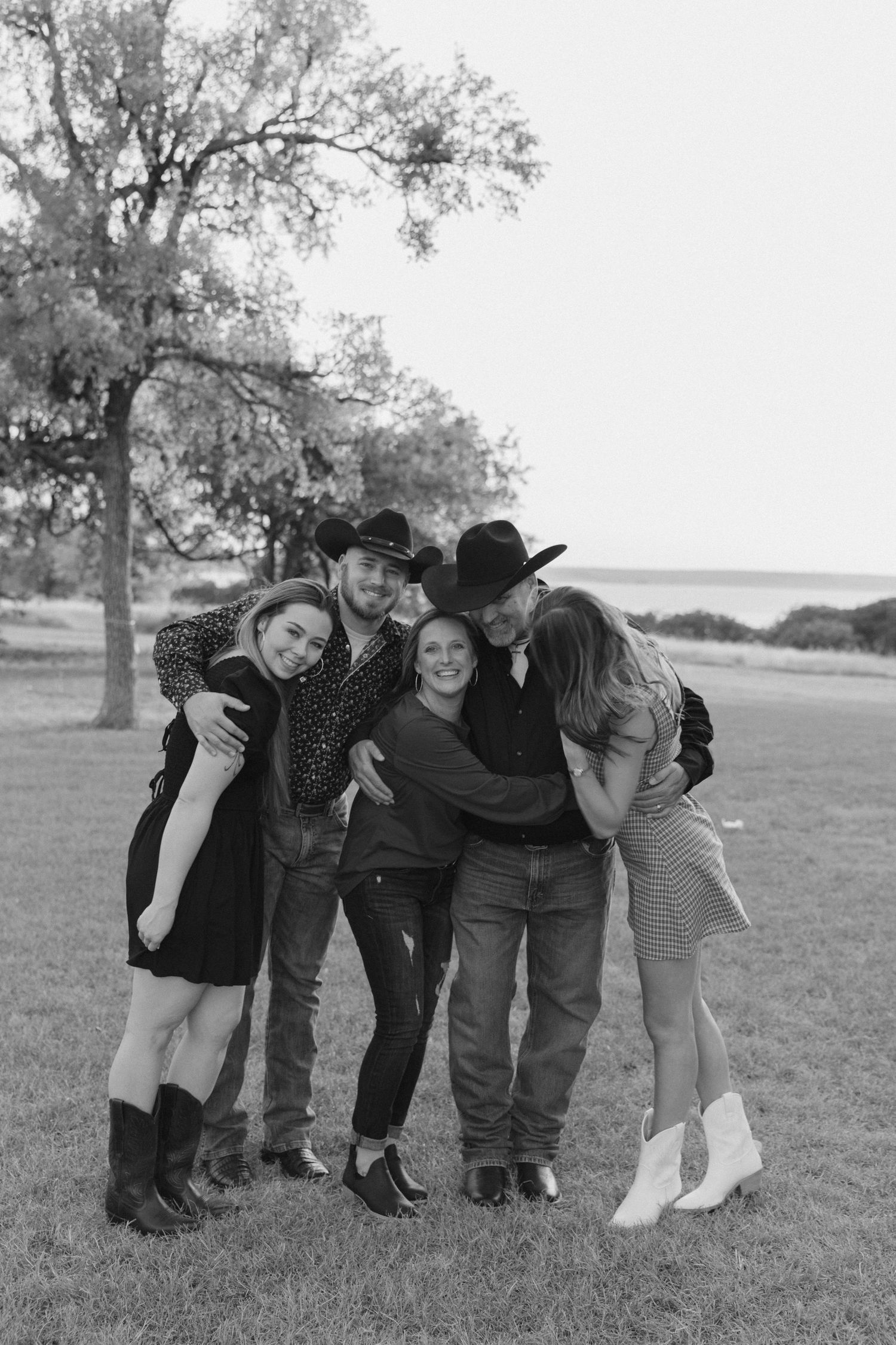 A playful group poses together on a grassy field in a series of three black and white photos.