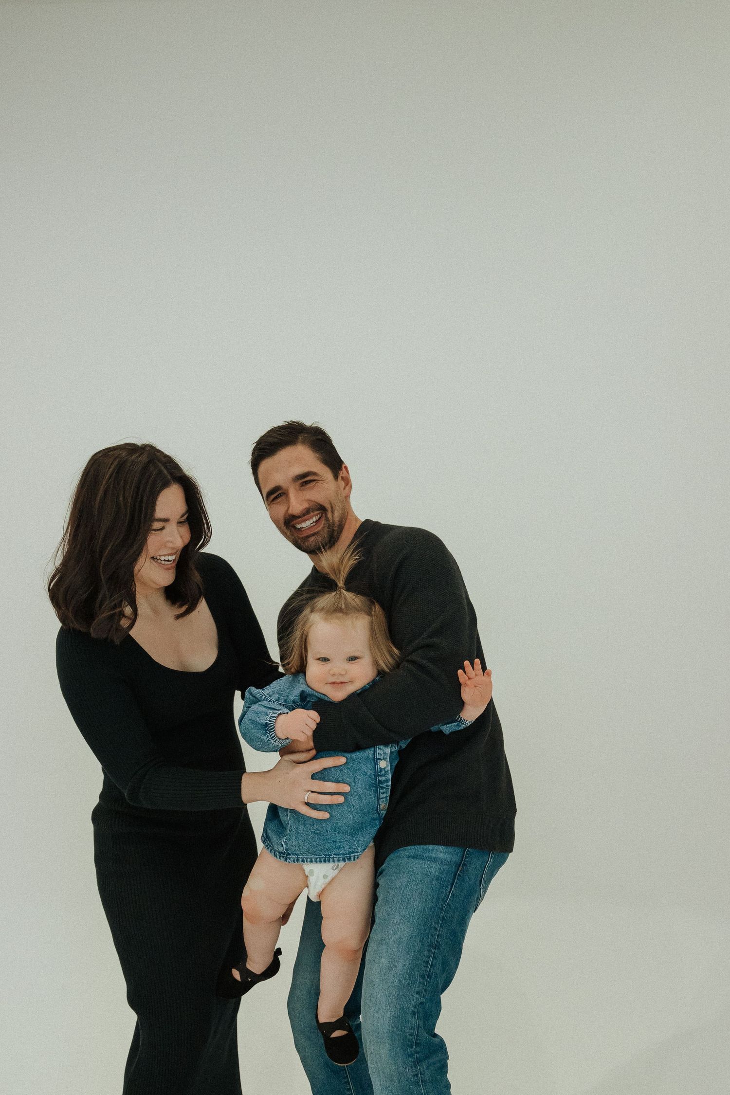 Family shares joyful moment together against white studio background.