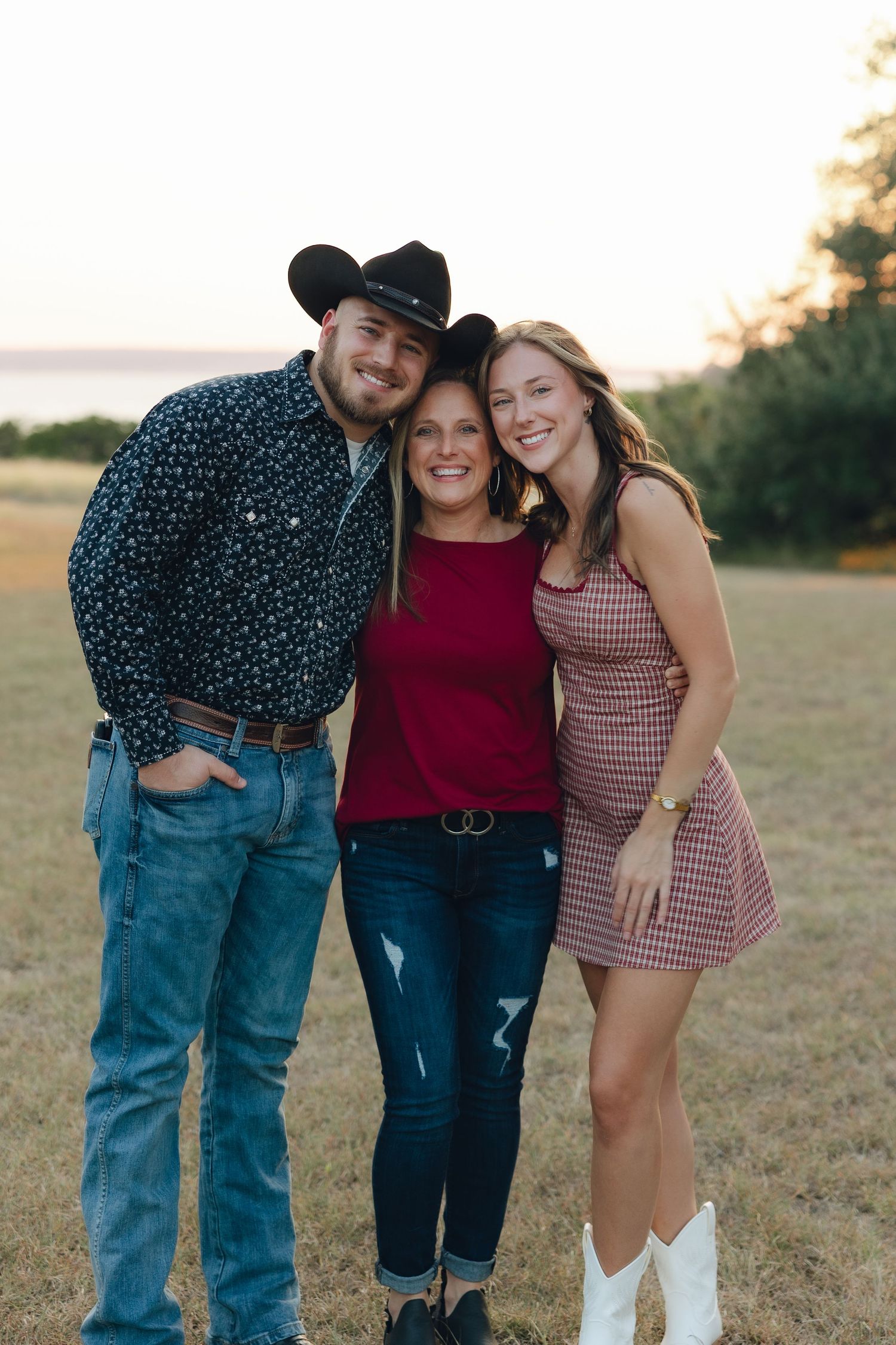 A group poses together in a casual outdoor photoshoot at sunset in a grassy field.