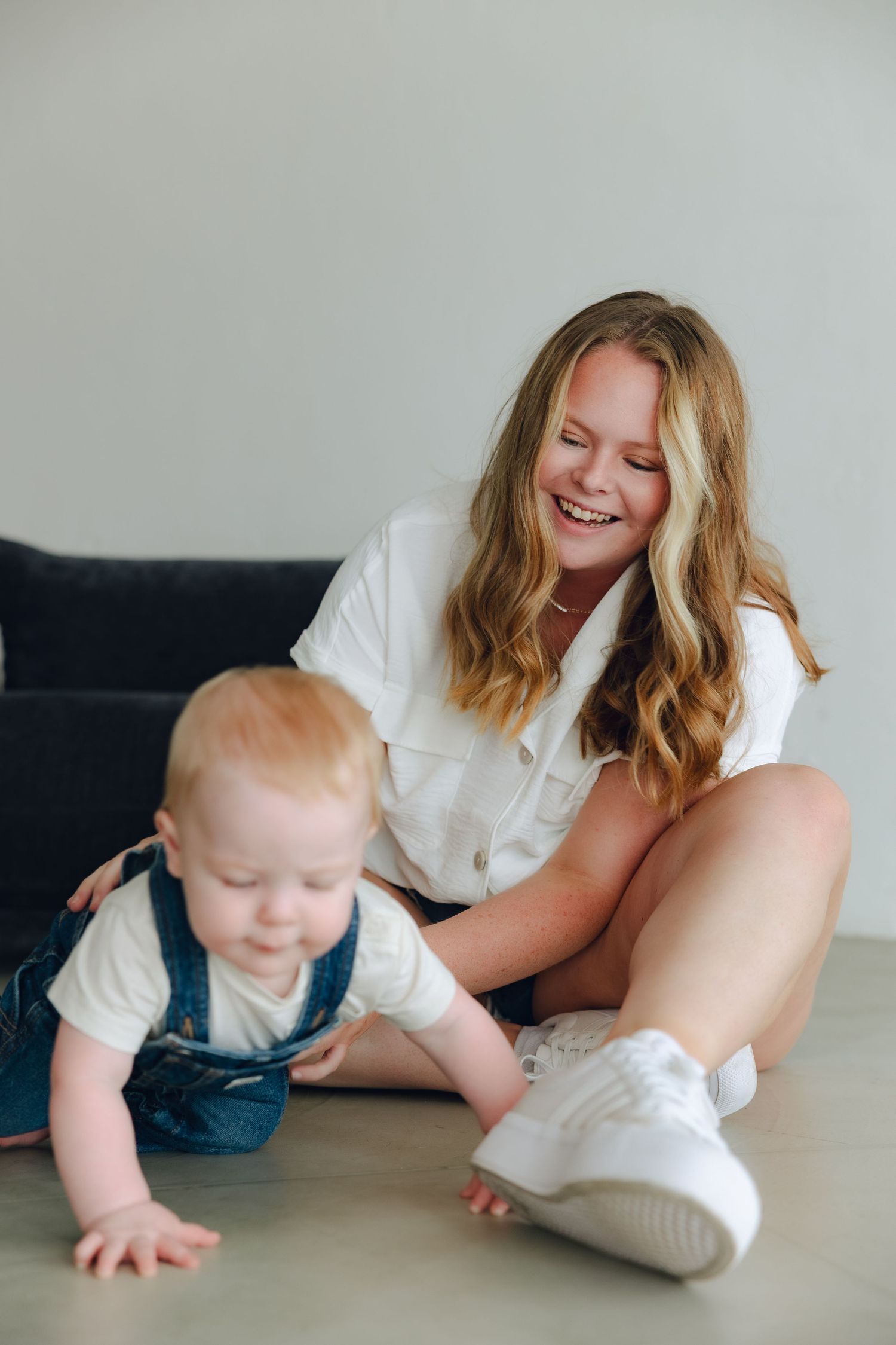 A candid lifestyle shot showing playtime between a parent and infant crawling on the floor.