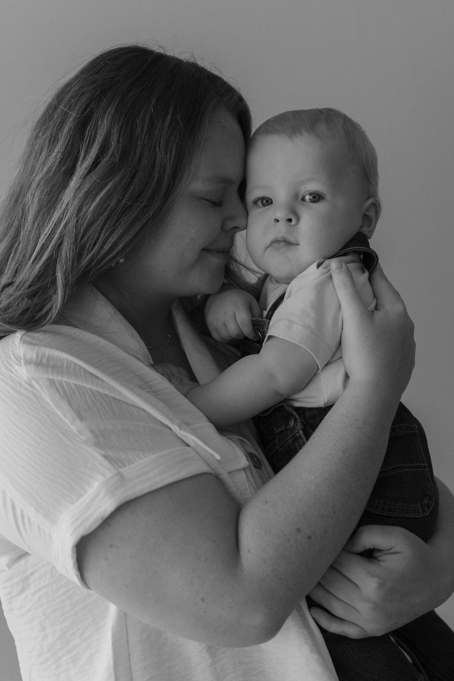Intimate black and white portrait of tender embrace between parent and baby.