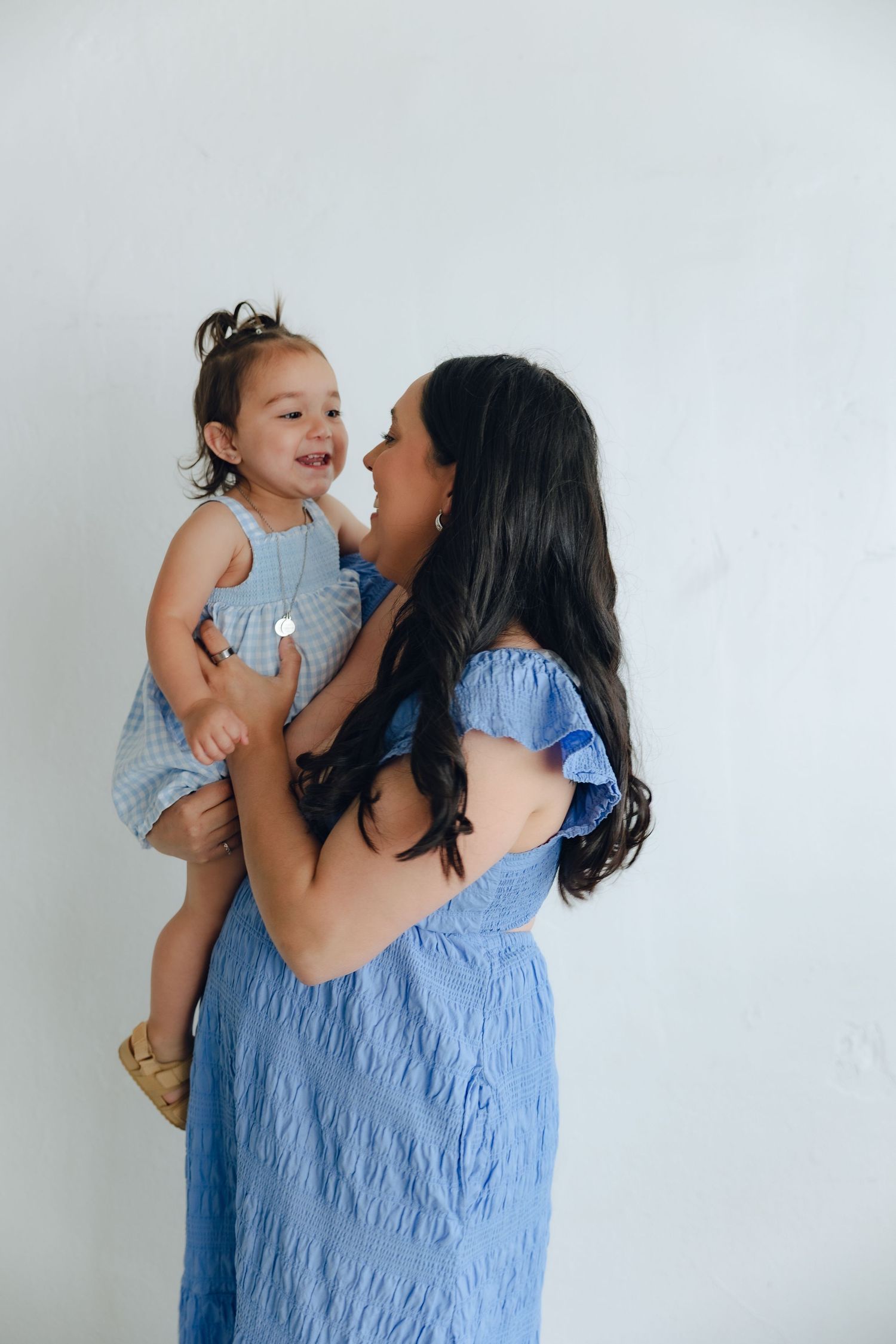 A tender moment between parent and child wearing matching blue outfits against a white wall.