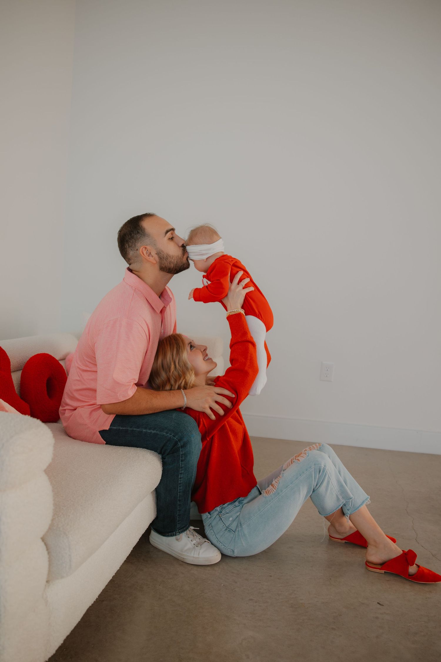 A relaxed family scene on a white couch with red and pink Valentine's Day decor.