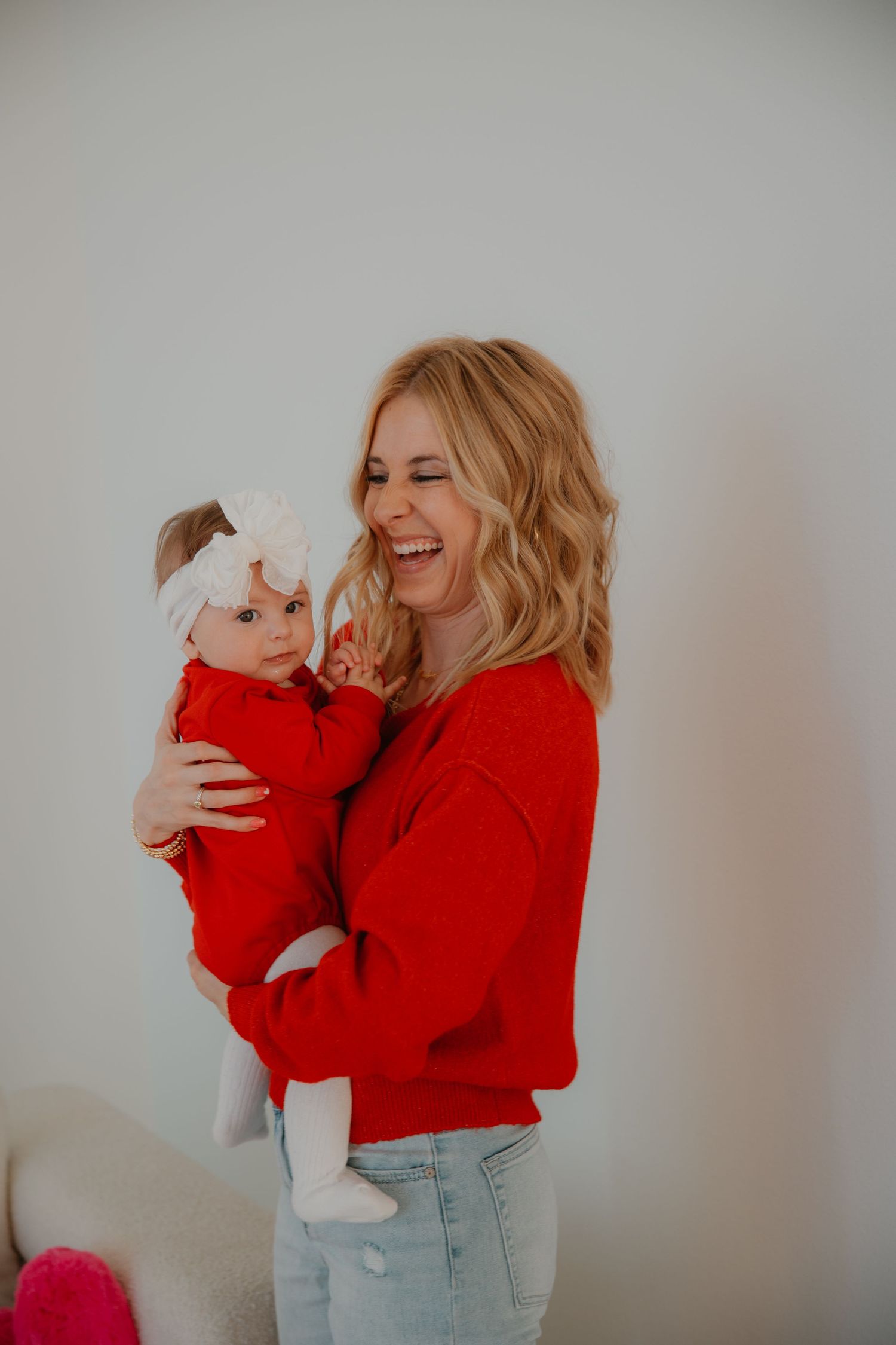 A heartwarming moment between parent and baby both wearing matching red outfits.