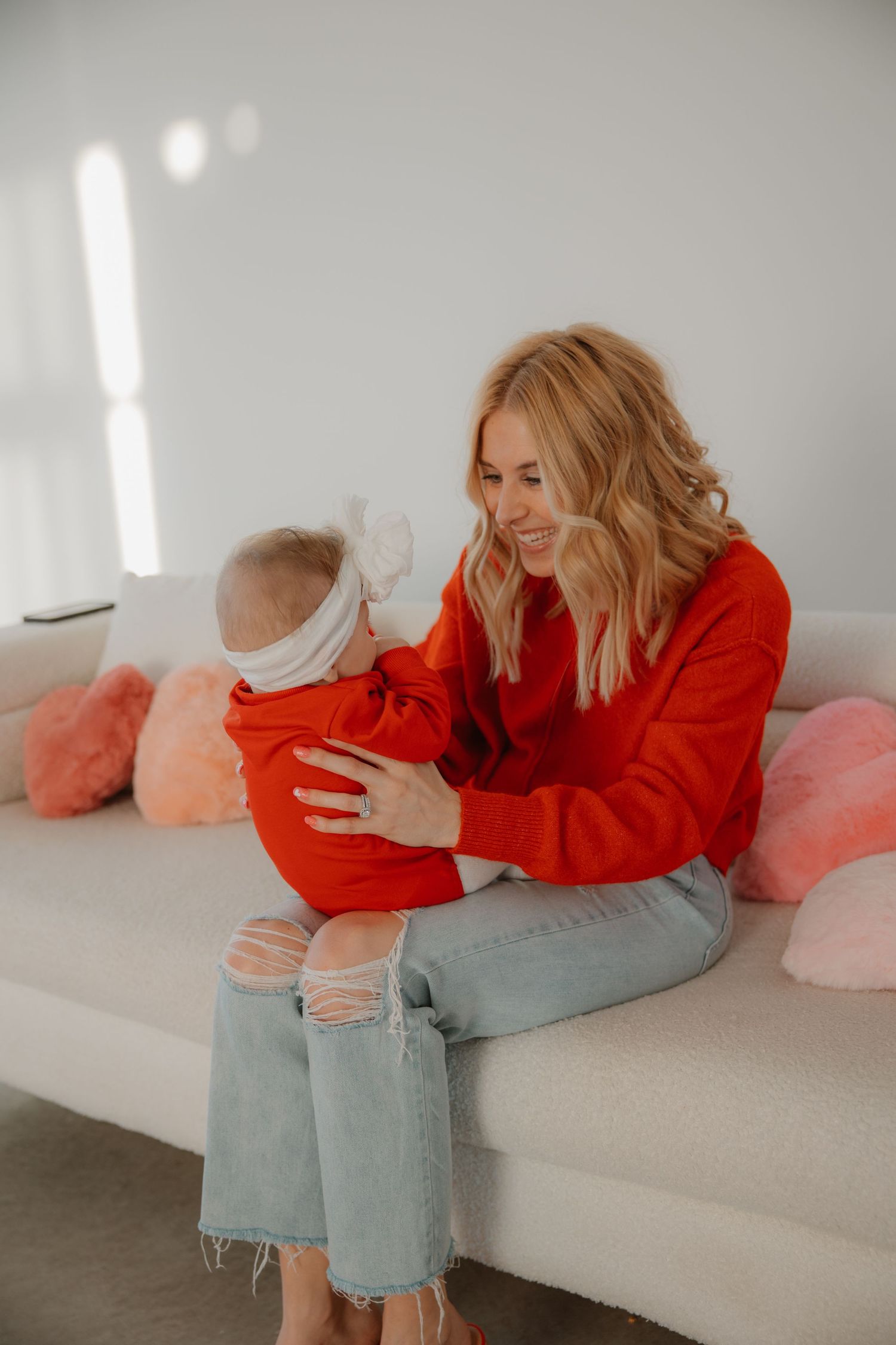 A tender moment shared between parent and baby on a white couch with pink pillows.