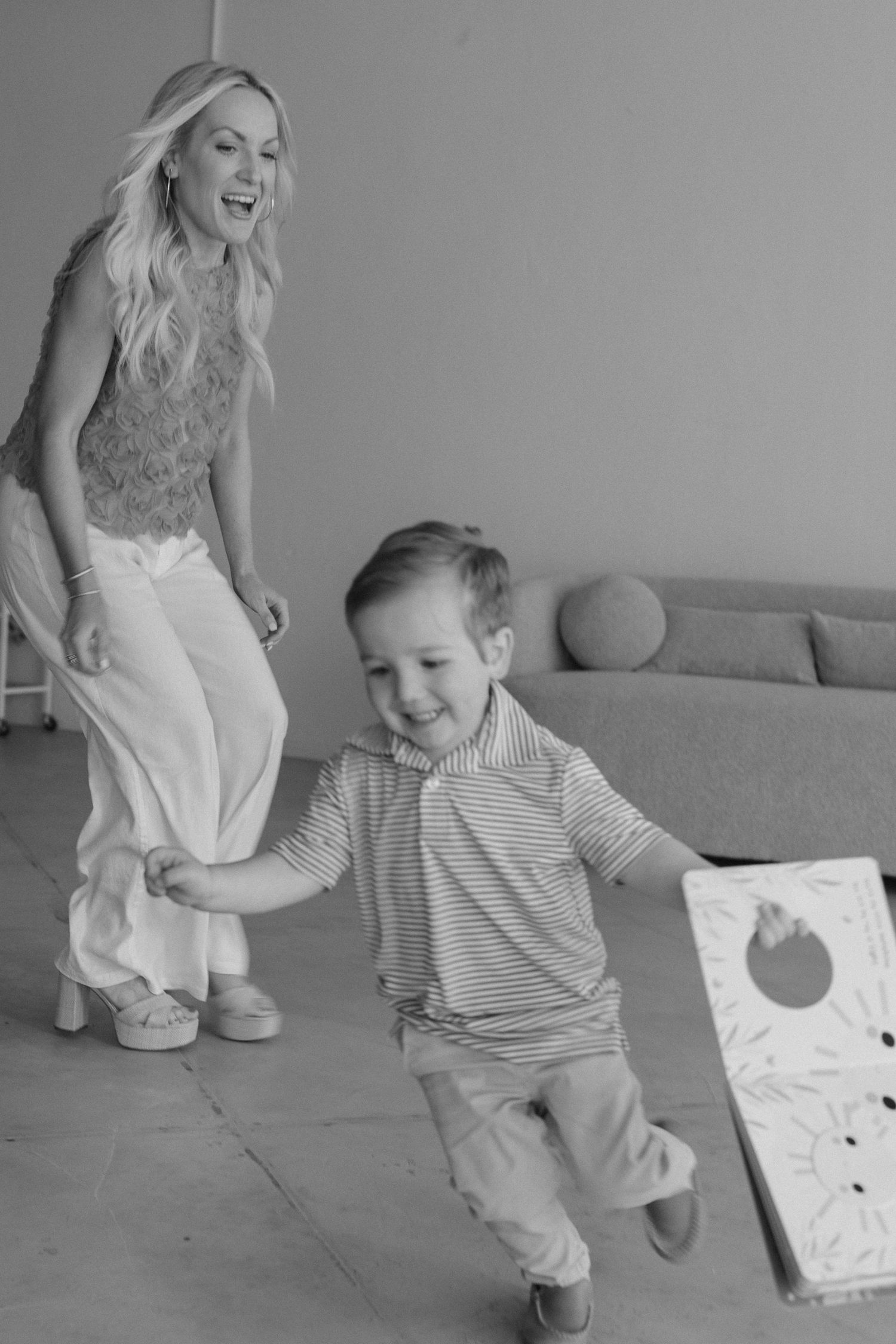 A joyful moment captured in black and white as a woman and young boy dance together in a casual indoor setting.