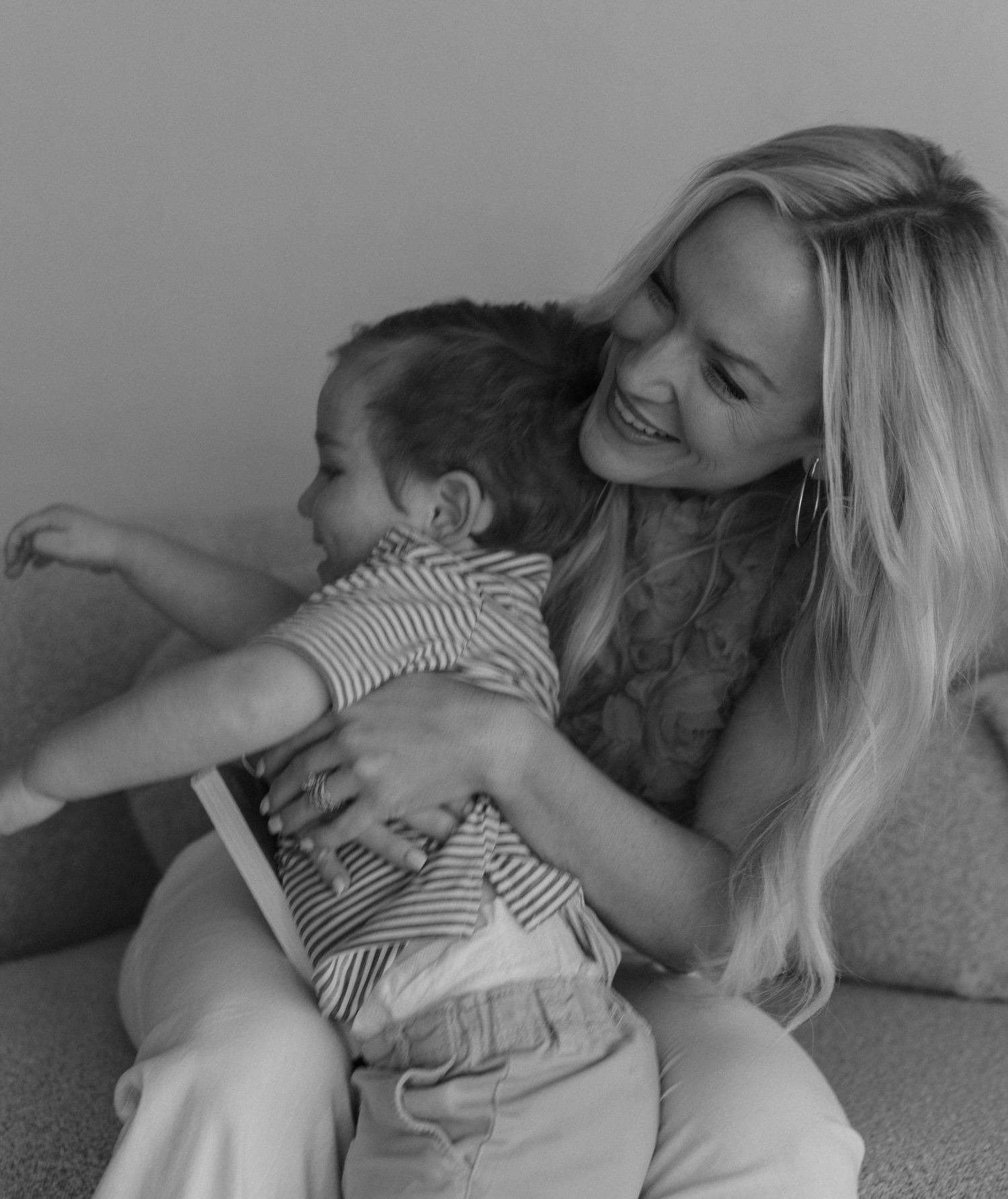 A tender black and white moment of connection and laughter between two people on a couch.