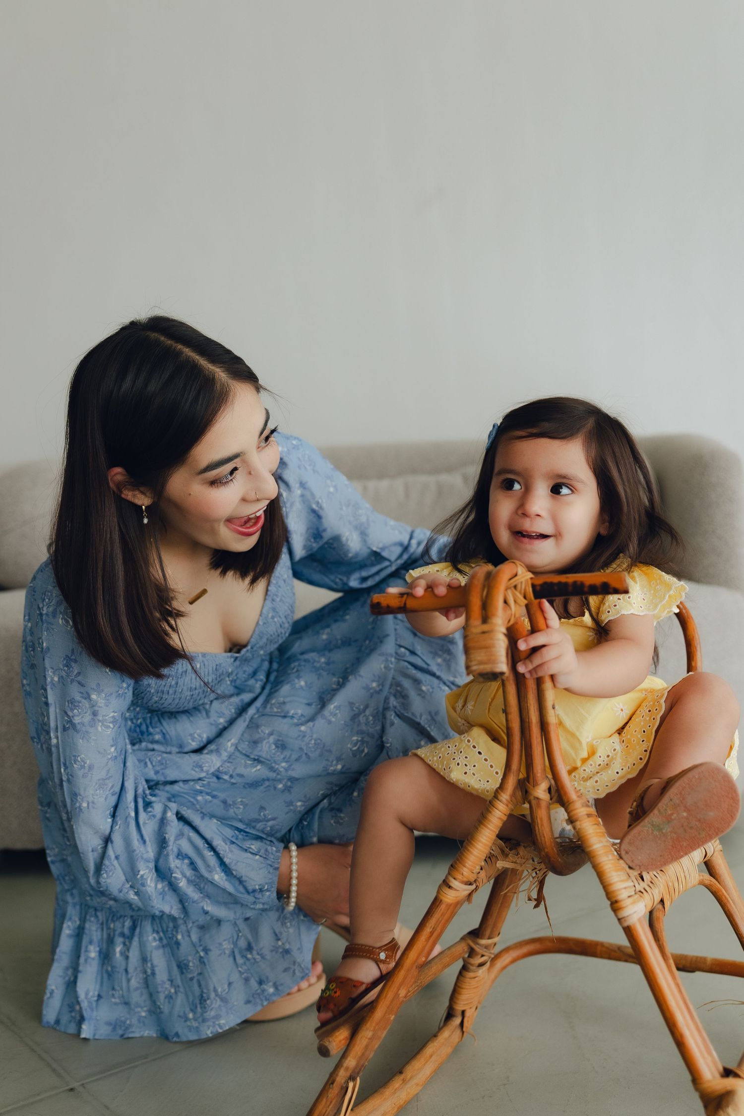 A parent and child spending quality time together on a wooden rocking horse while wearing casual blue and yellow outfits.