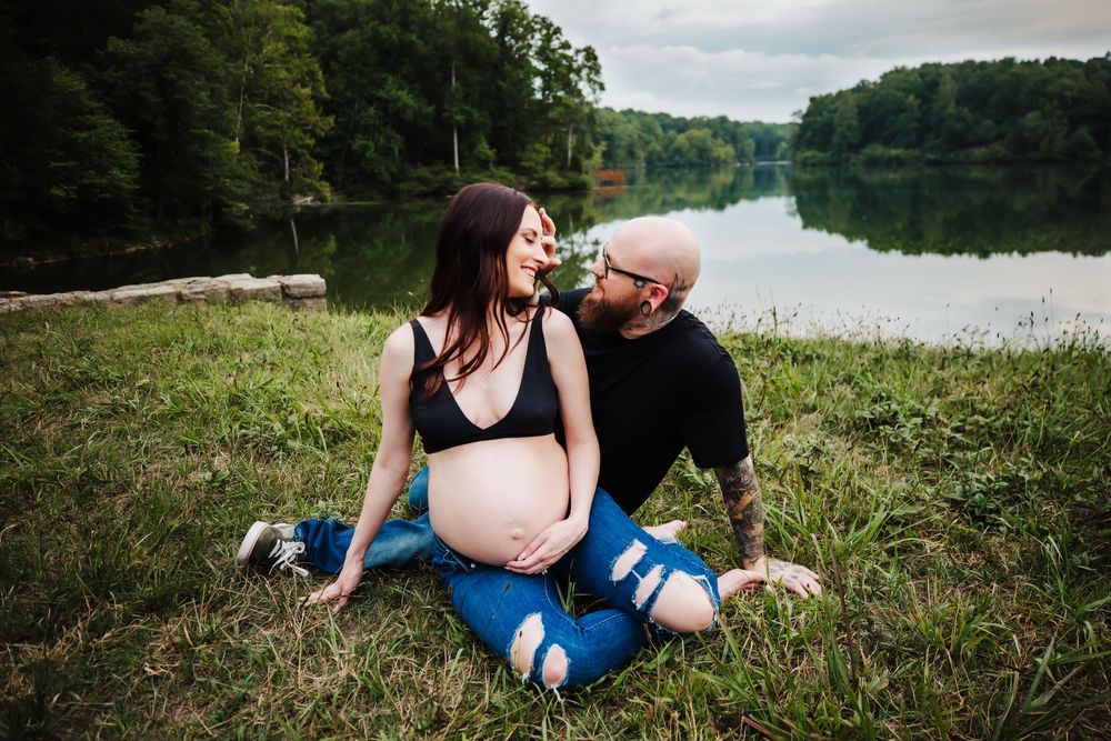 Pregnant woman and her husband sitting in front of lake at Montgomery Bell State Park
